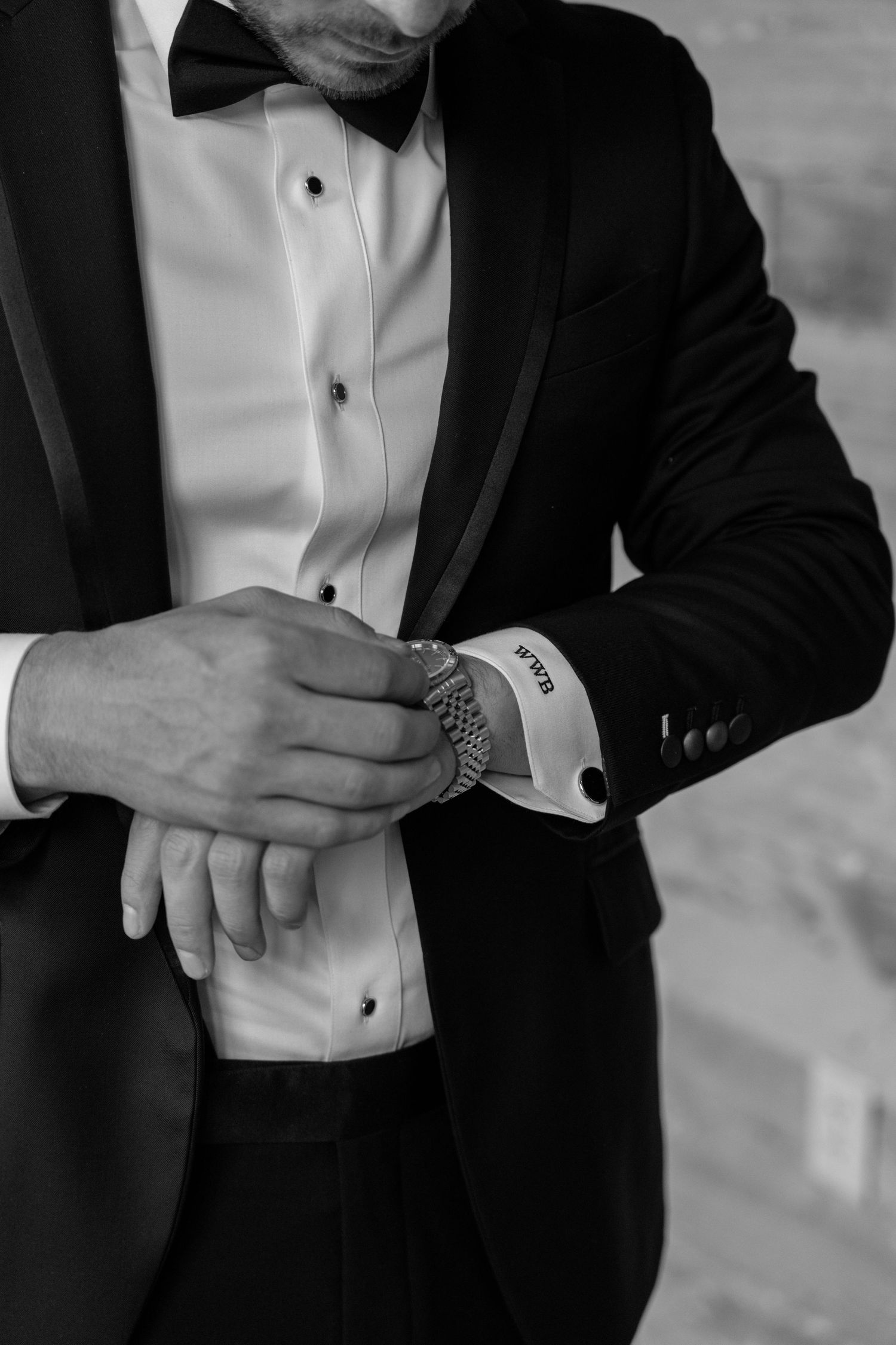Black and white detail of hands adjusting formal tuxedo cuff.