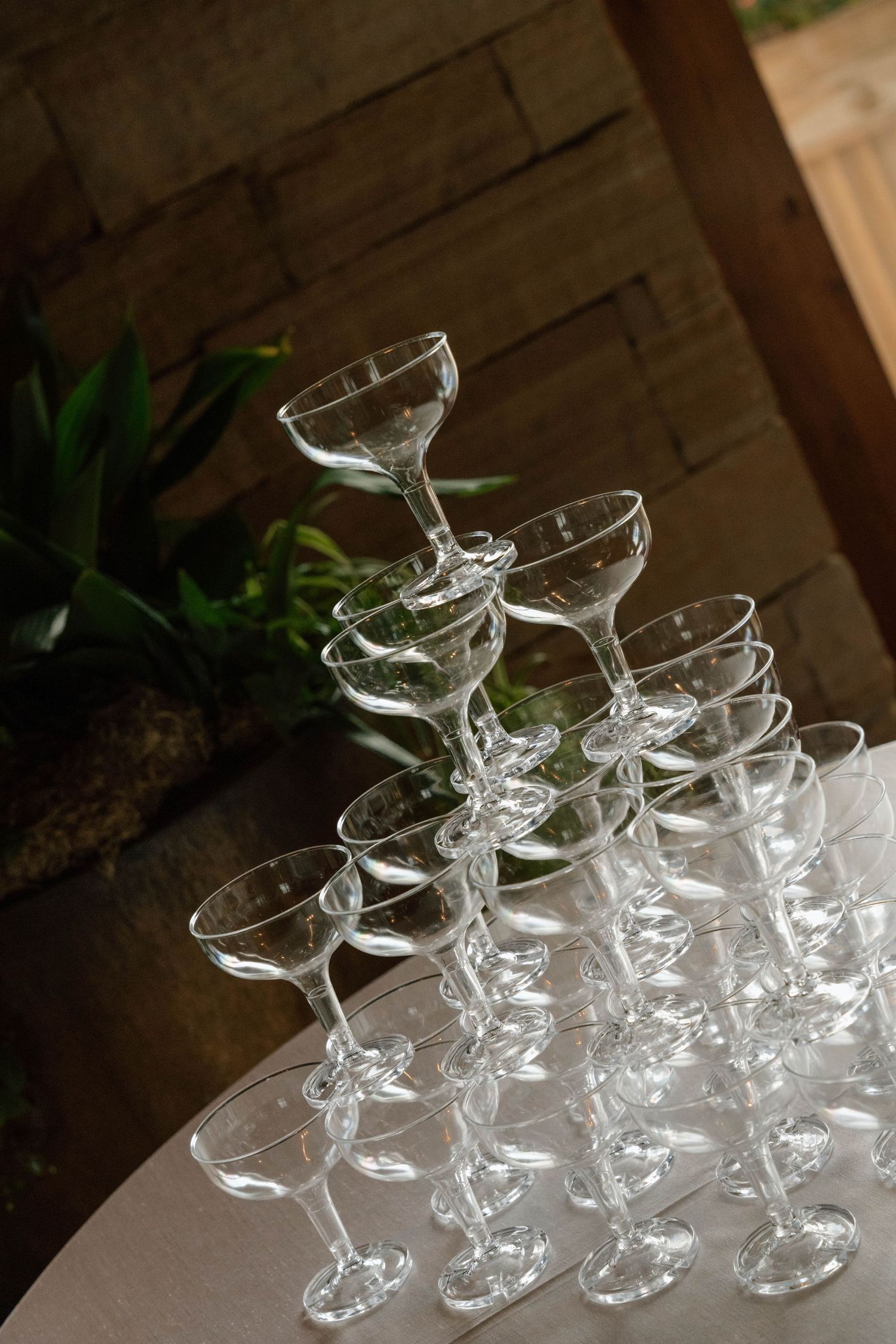 A pyramid stack of empty champagne glasses arranged on a white table at an event.