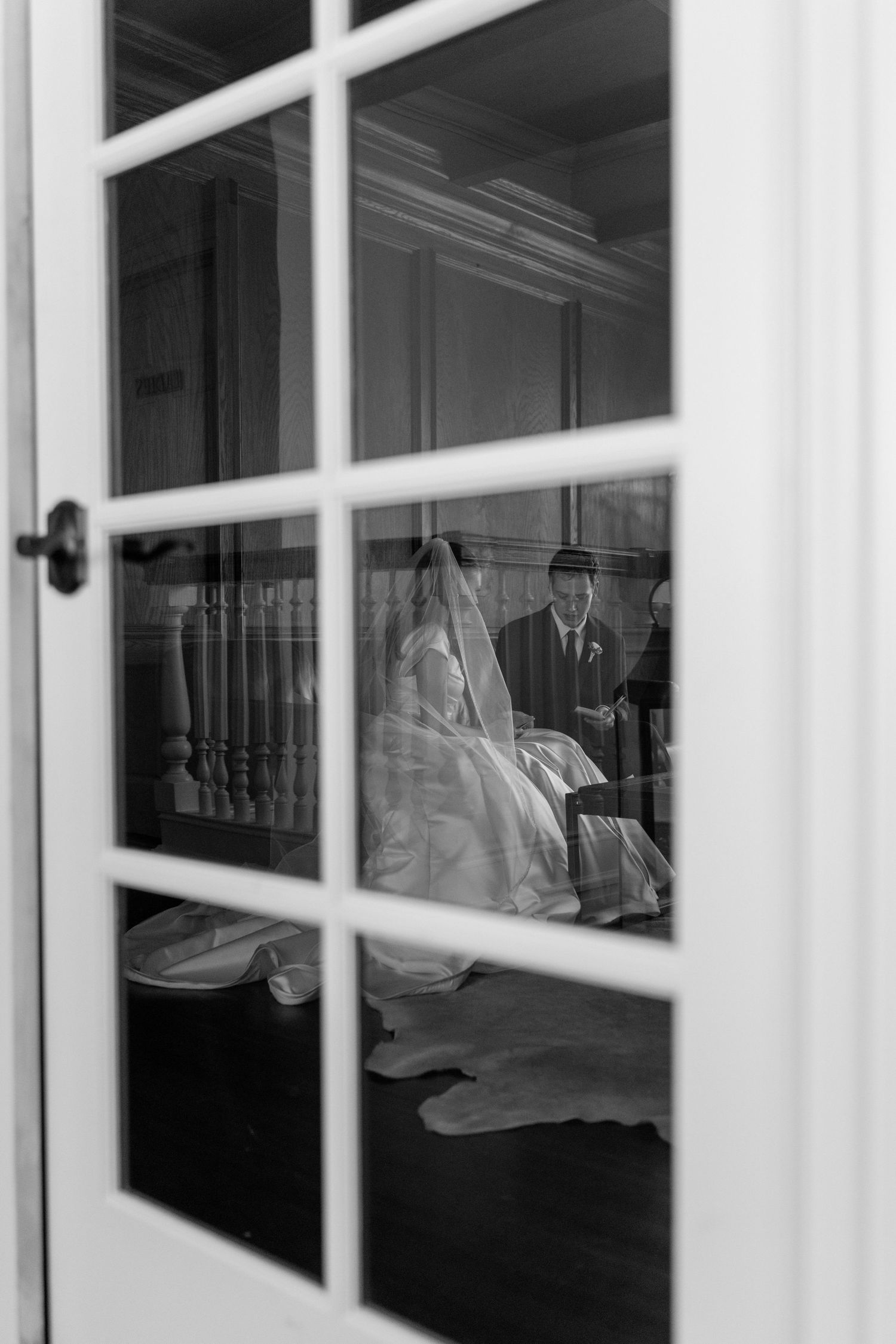 White window panes frame a reflection of formal wedding attire in an interior space.