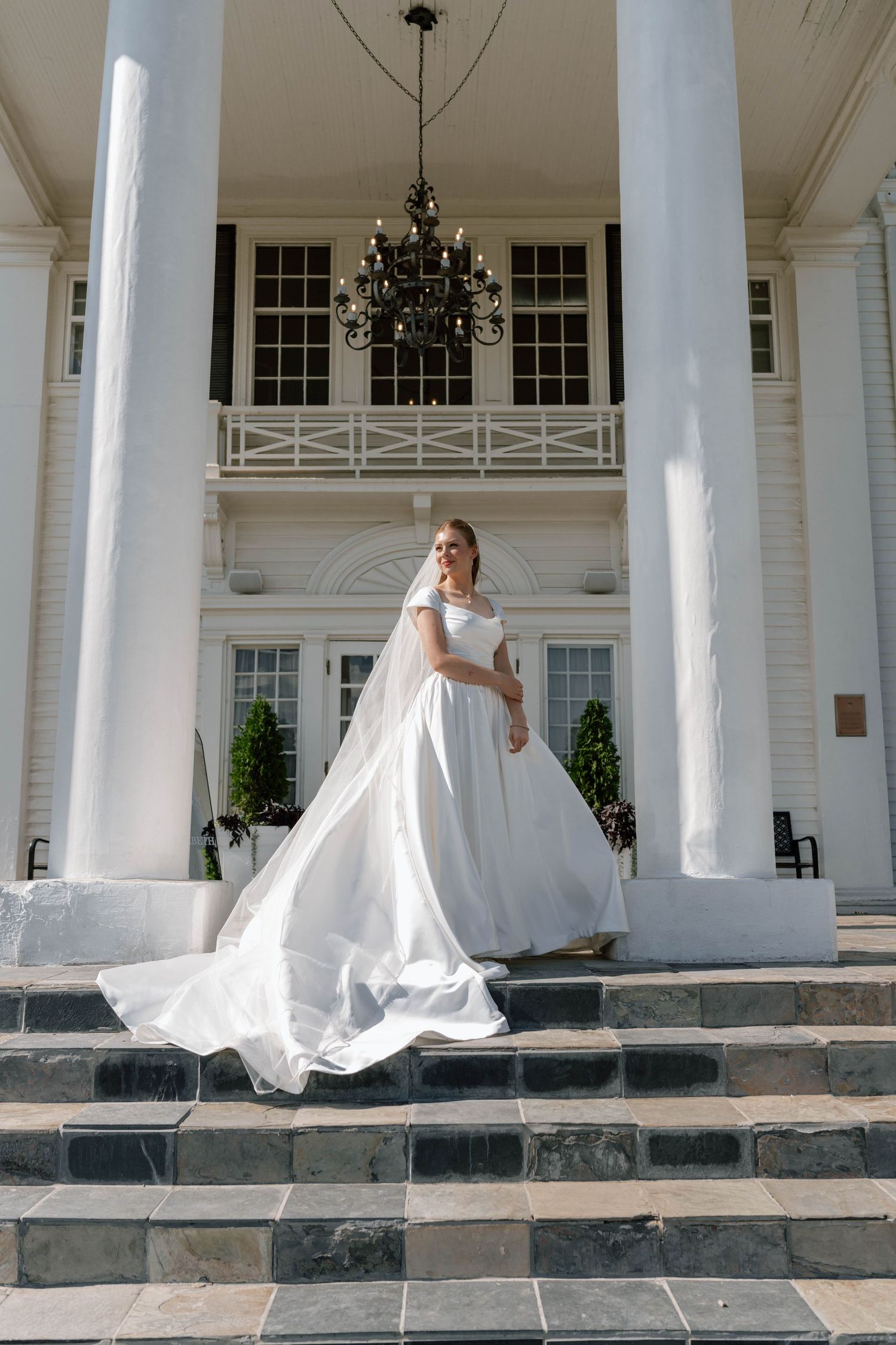 Classic white colonial building with grand columns and stone steps in bright daylight.
