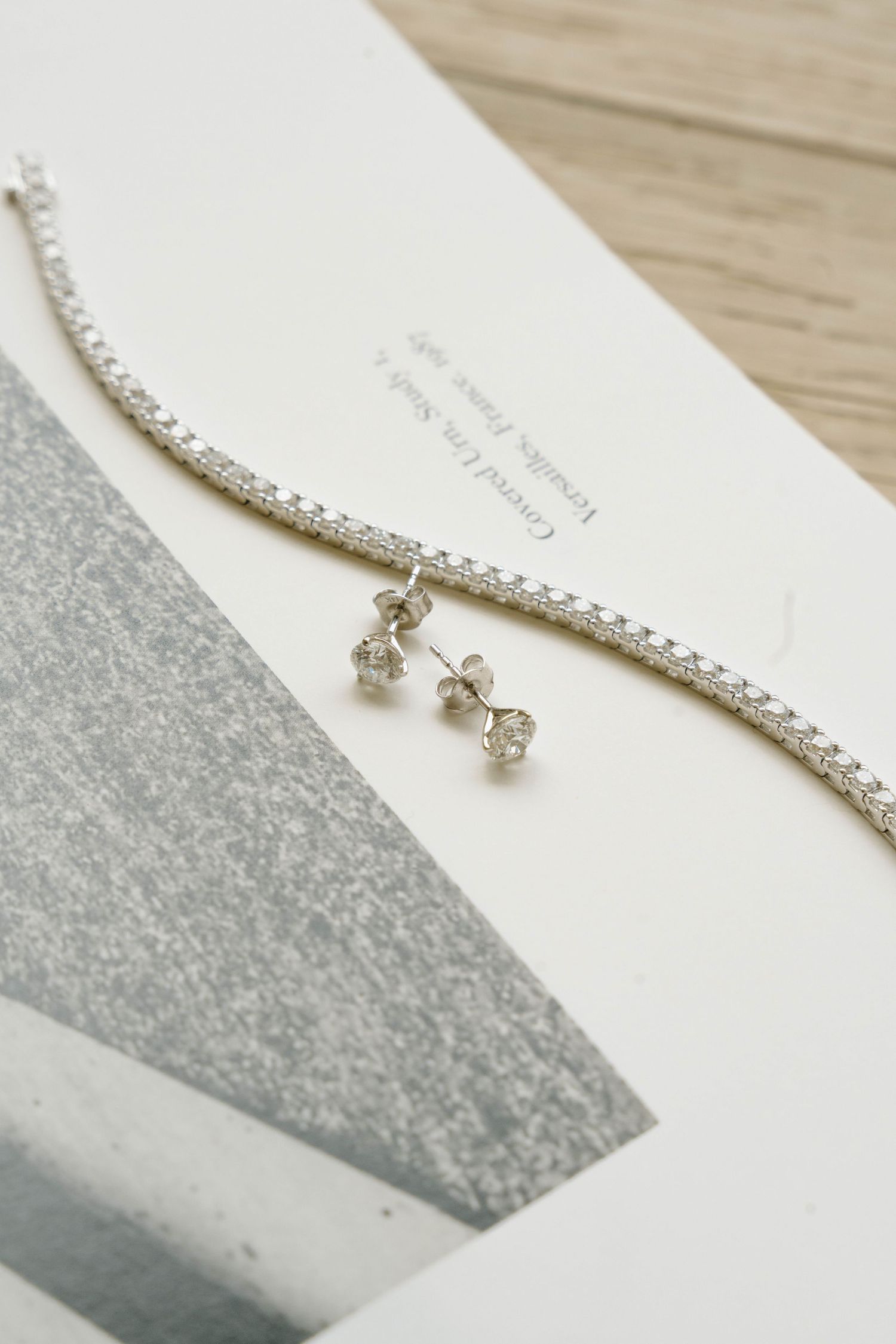 Delicate crystal bridal jewelry set against a white and silver background.
