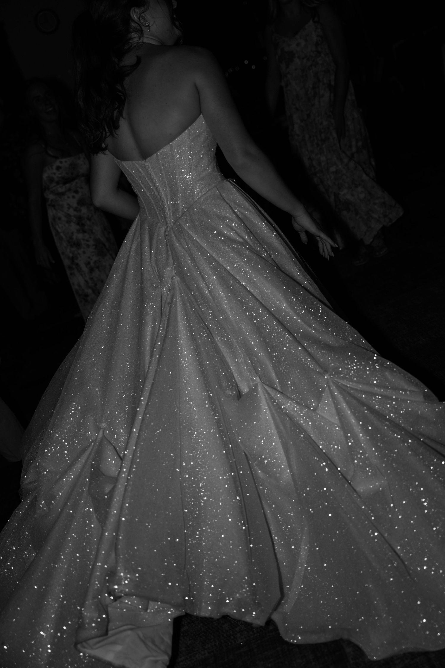 Black and white photo of a woman in a sparkling strapless ballgown, glittering details catching light.