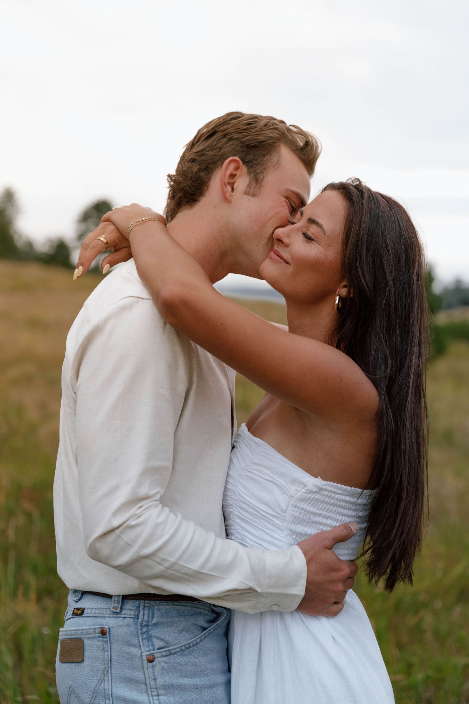 An intimate embrace captured in golden light against rolling hills.