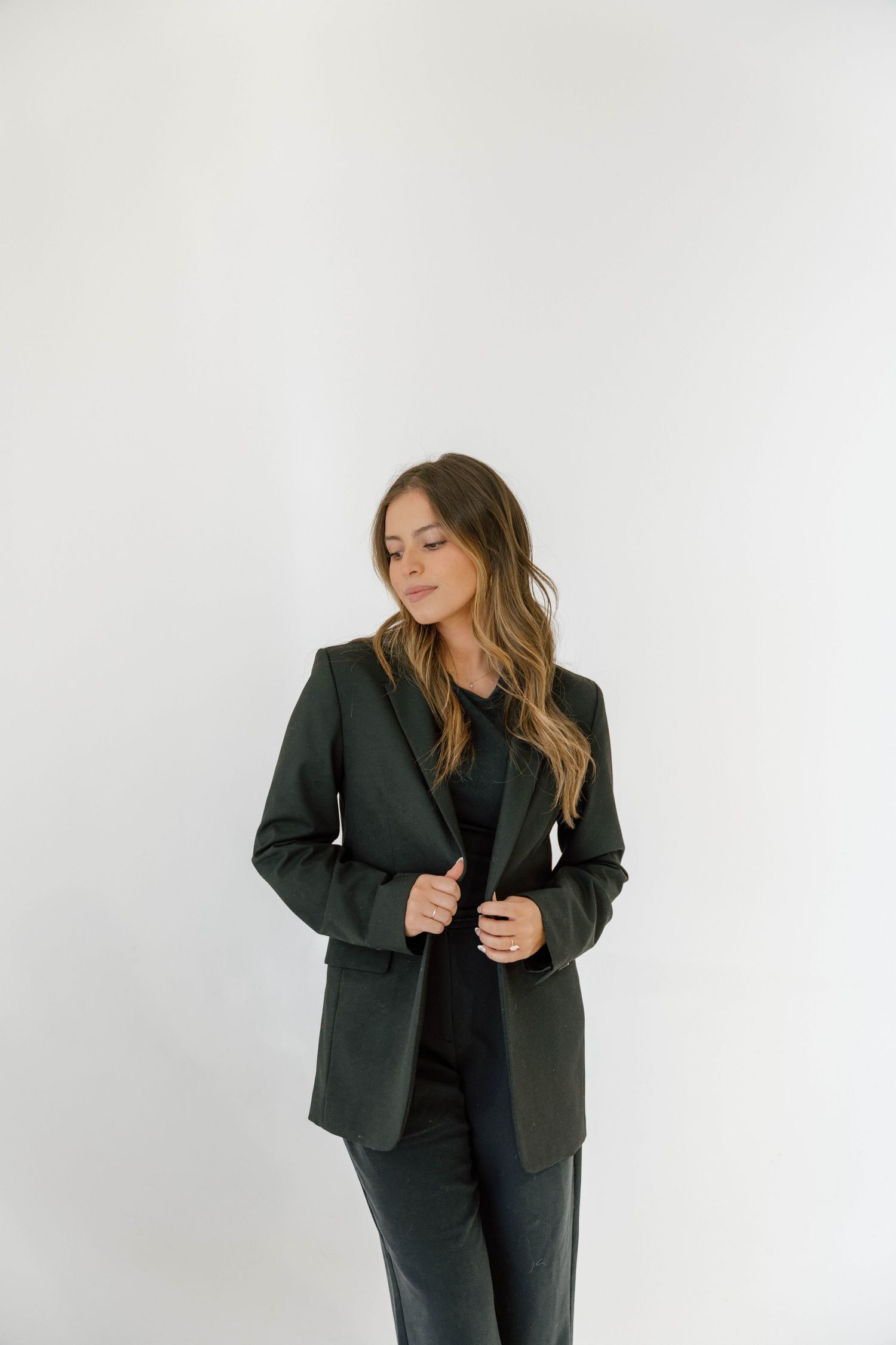 Professional portrait of woman in dark blazer against white background.