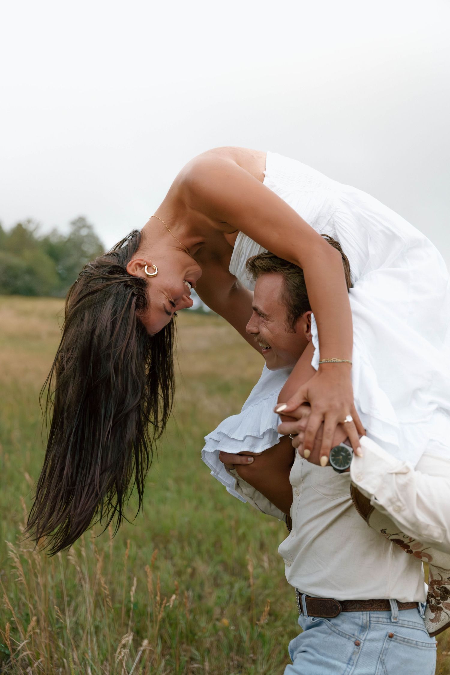 A playful dip pose in a mountain meadow with flowing white dress.