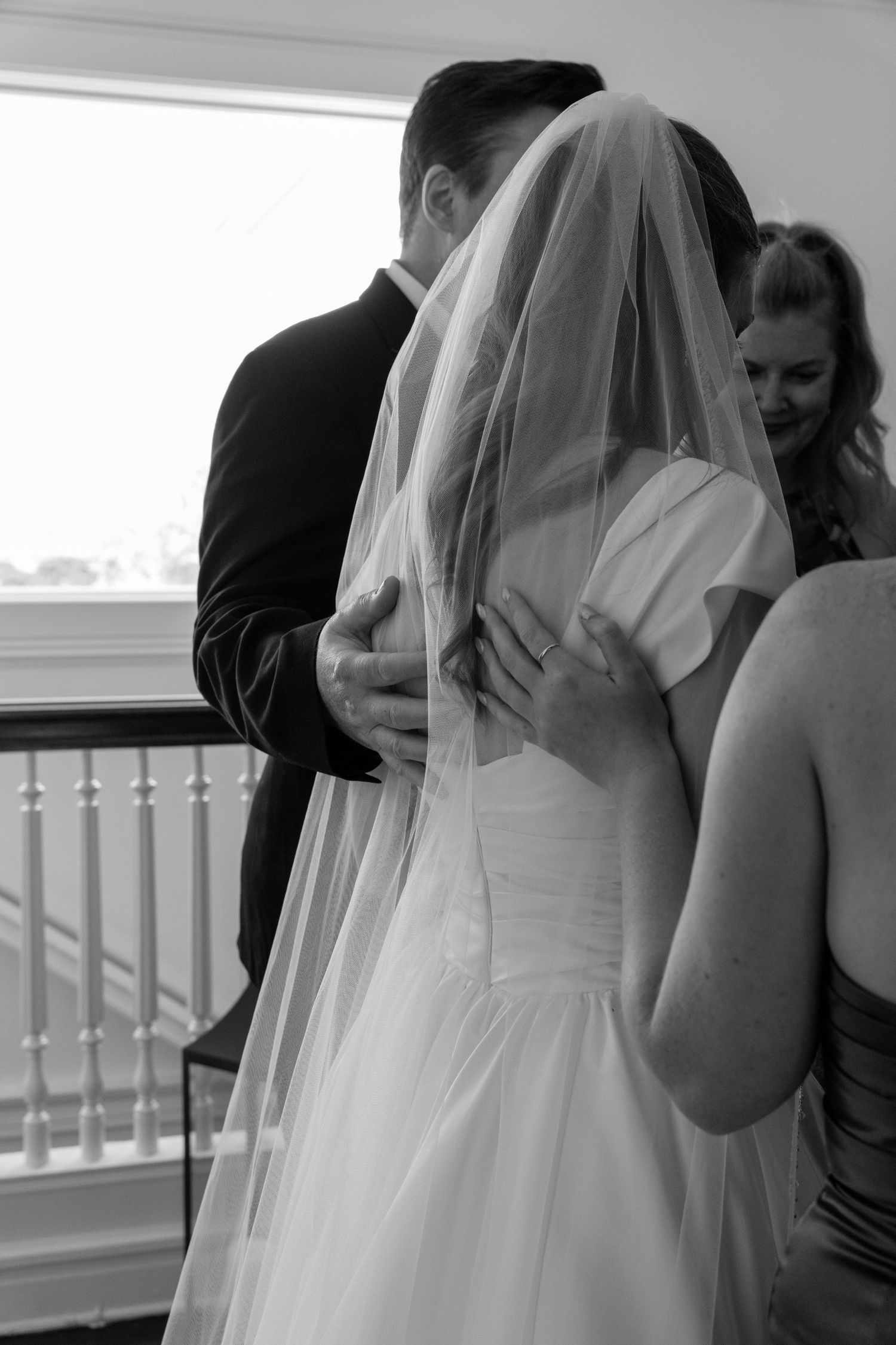 A bride in white dress and veil stands in an elegant indoor setting.
