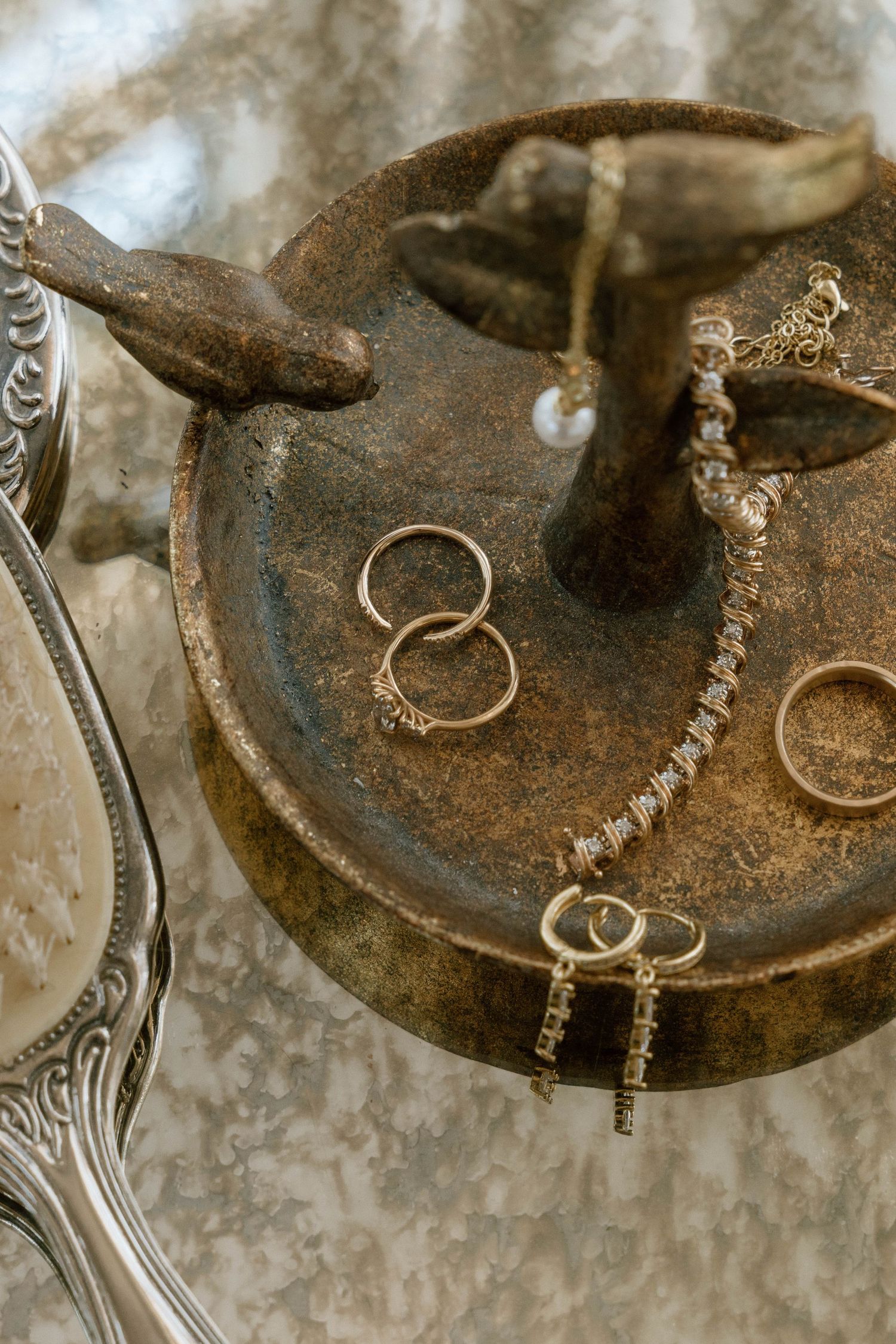 Vintage key and wedding rings arranged on an antique metal surface.