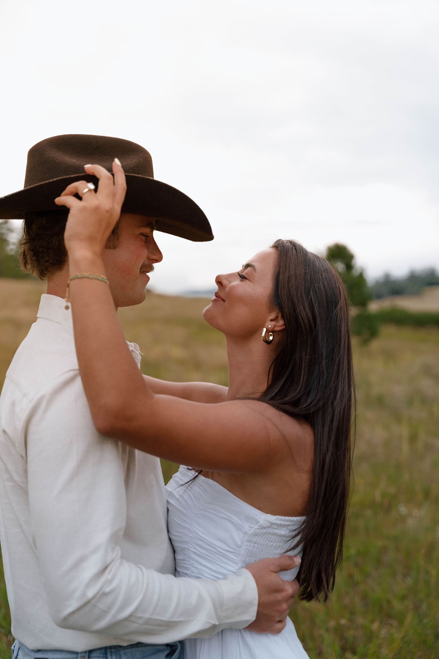 A tender moment shared between lovers in western attire against mountain scenery.