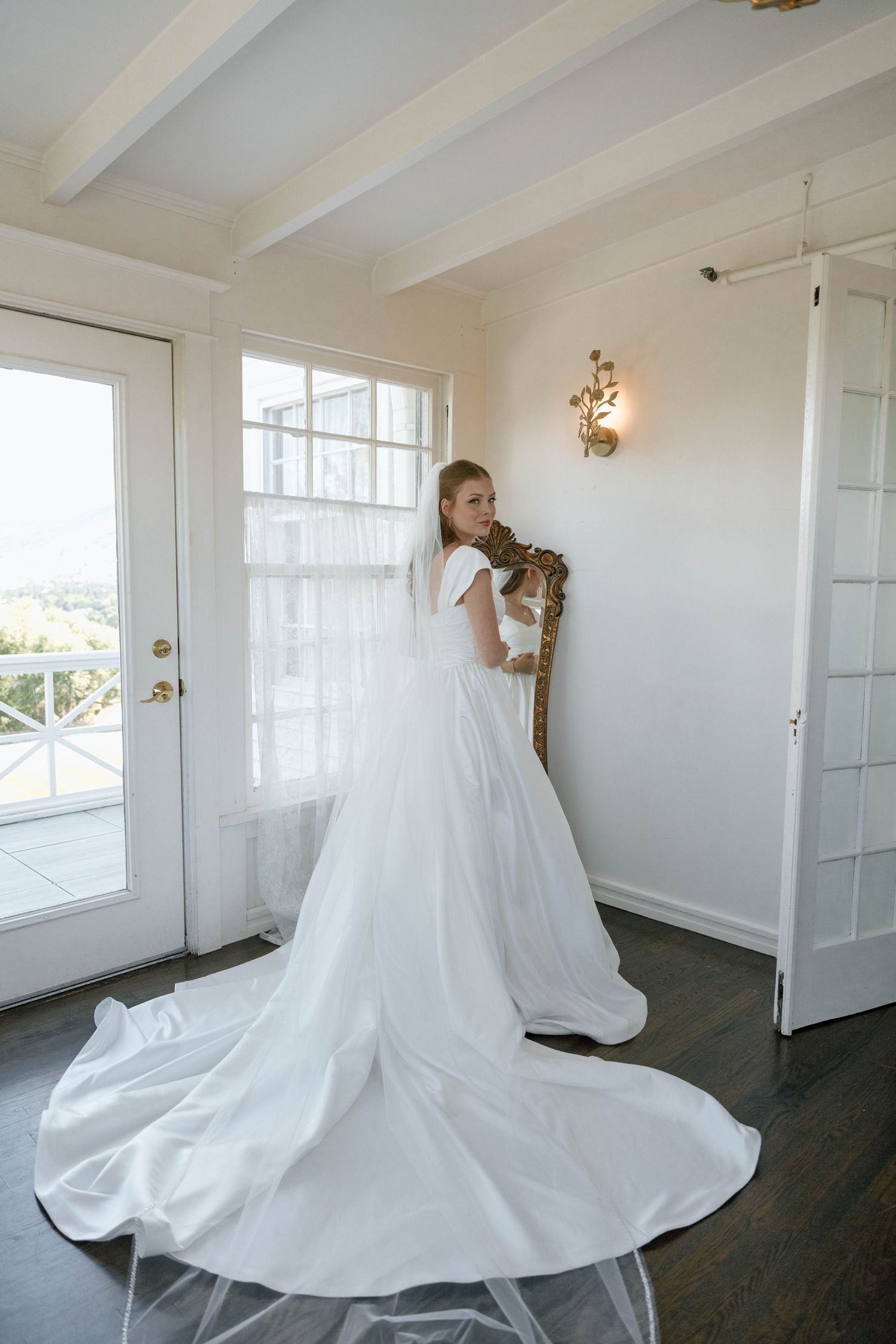 A flowing white wedding dress twirls in a bright, minimalist room with white walls.