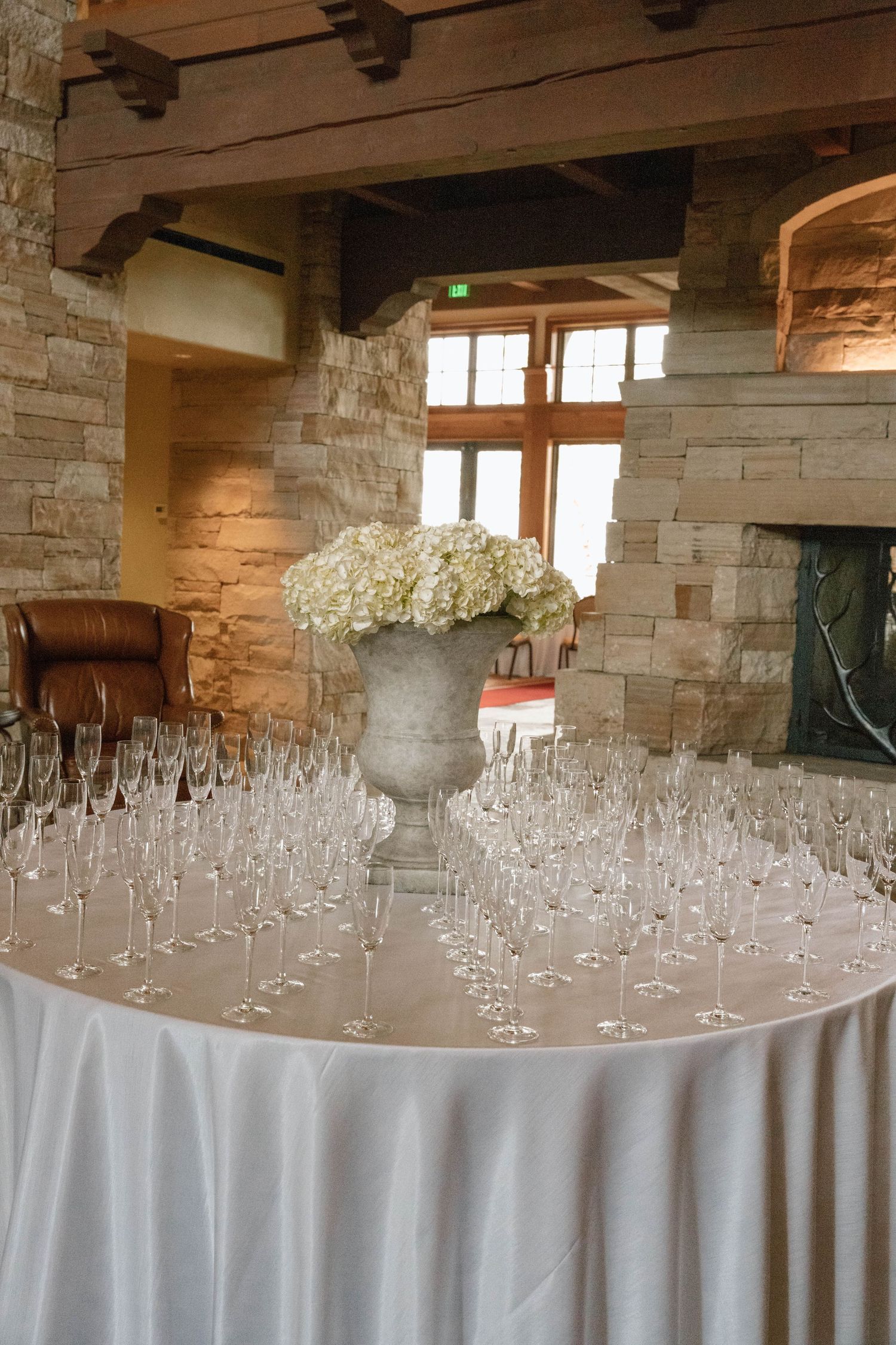 Elegant table setting with white hydrangeas in stone urn and champagne glasses.