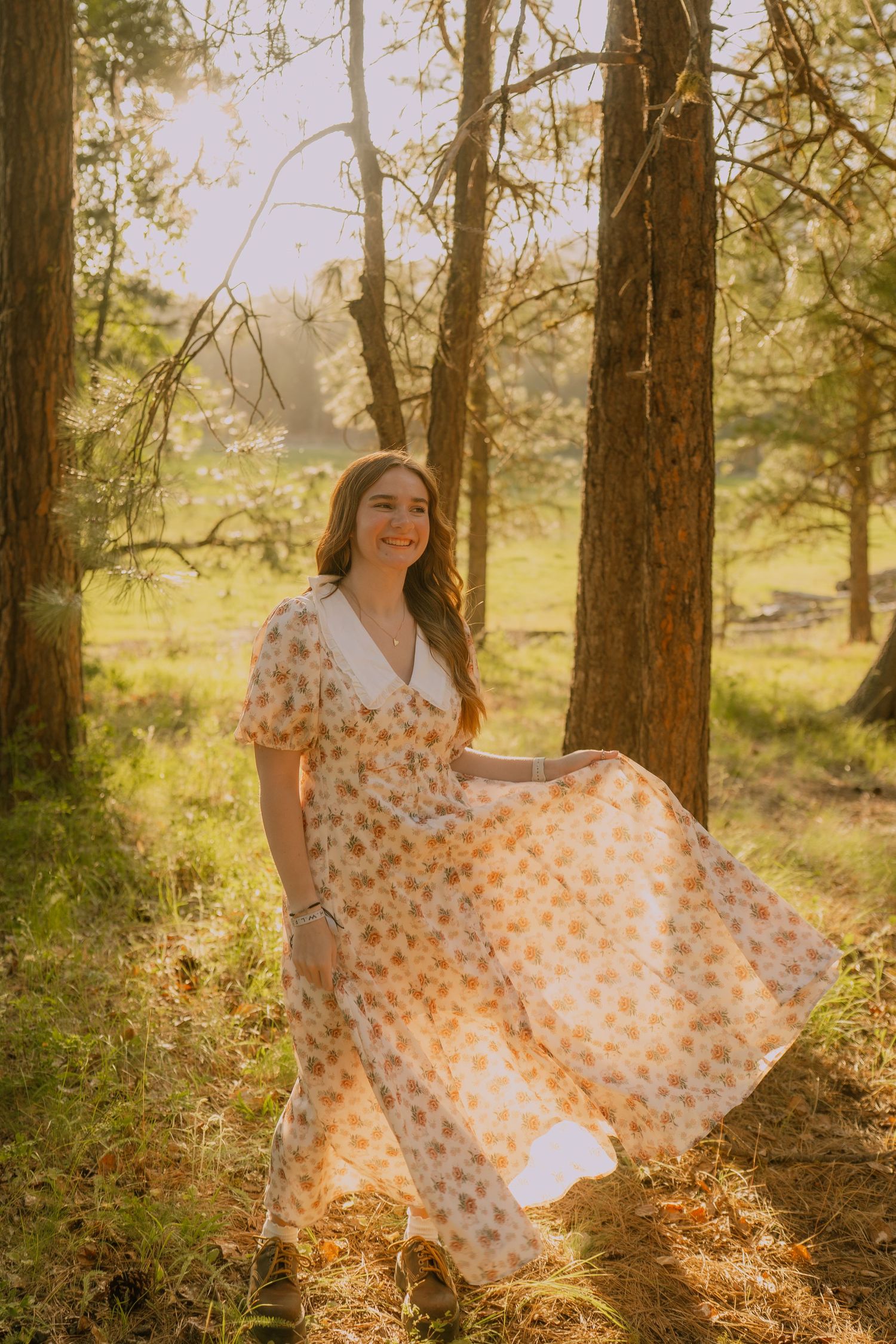 A flowing floral dress twirls gracefully among sunlit pine trees in a dreamy forest setting.
