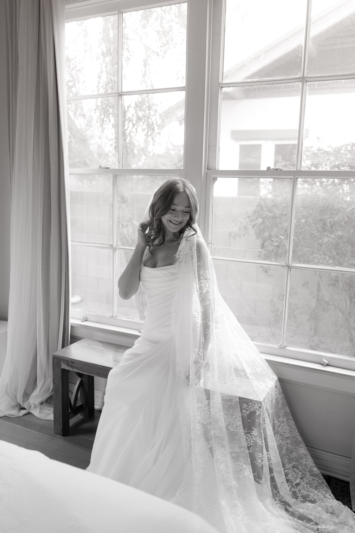 A series of black and white photos showing delicate lace wedding dress details near sunlit windows.