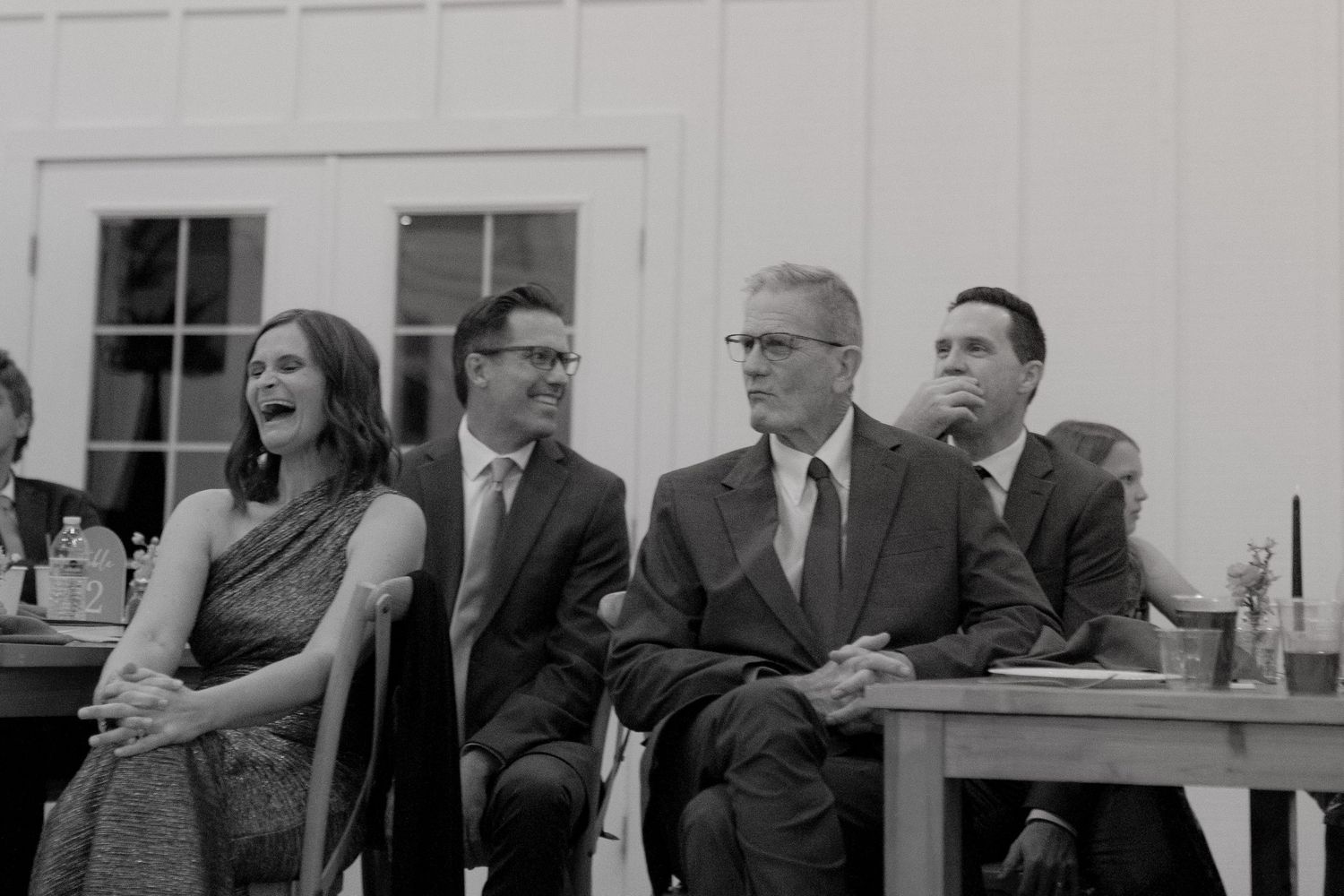A series of black and white photos showing people laughing and smiling during what appears to be a meeting or gathering.
