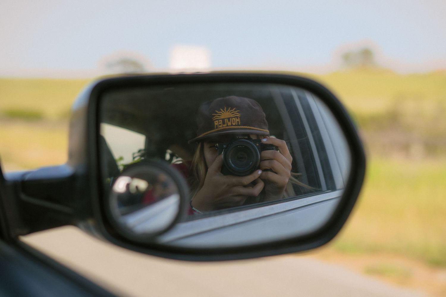 A series of car side mirror reflections showing rural landscapes and road views during a journey.