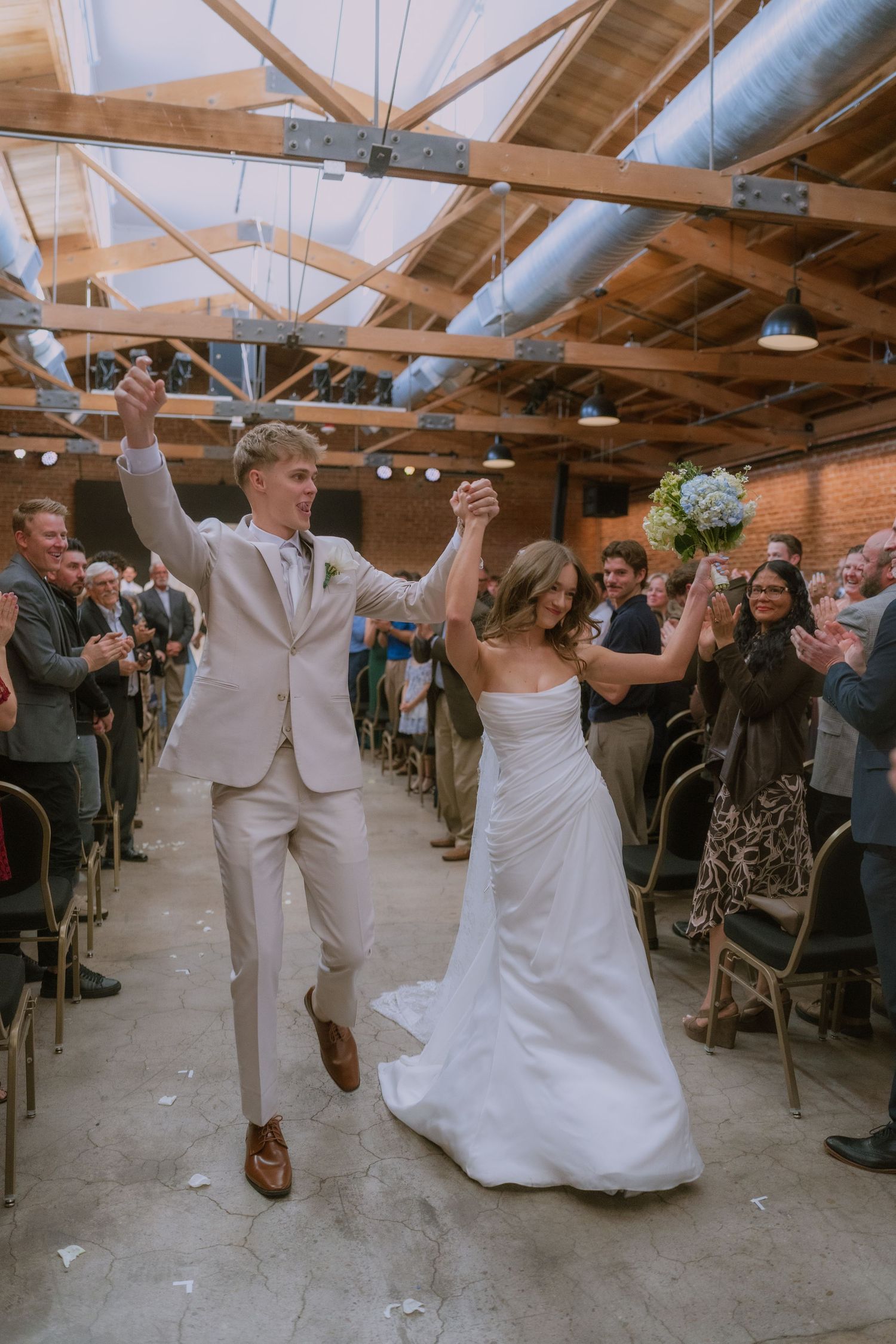 Newlywed couple performs a celebratory dance sequence at their wedding reception in an industrial-style venue.
