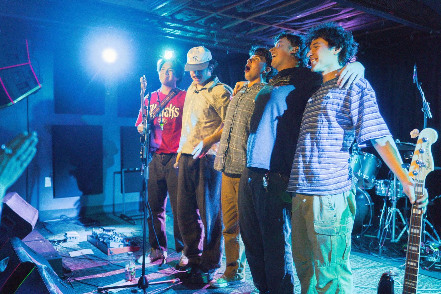 Performers lined up on stage under bright blue theatrical lighting during a show production.