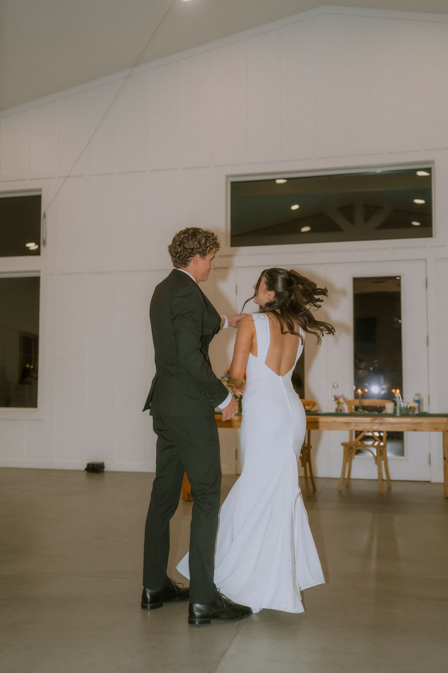 Couple dances together in an elegant white indoor venue space.
