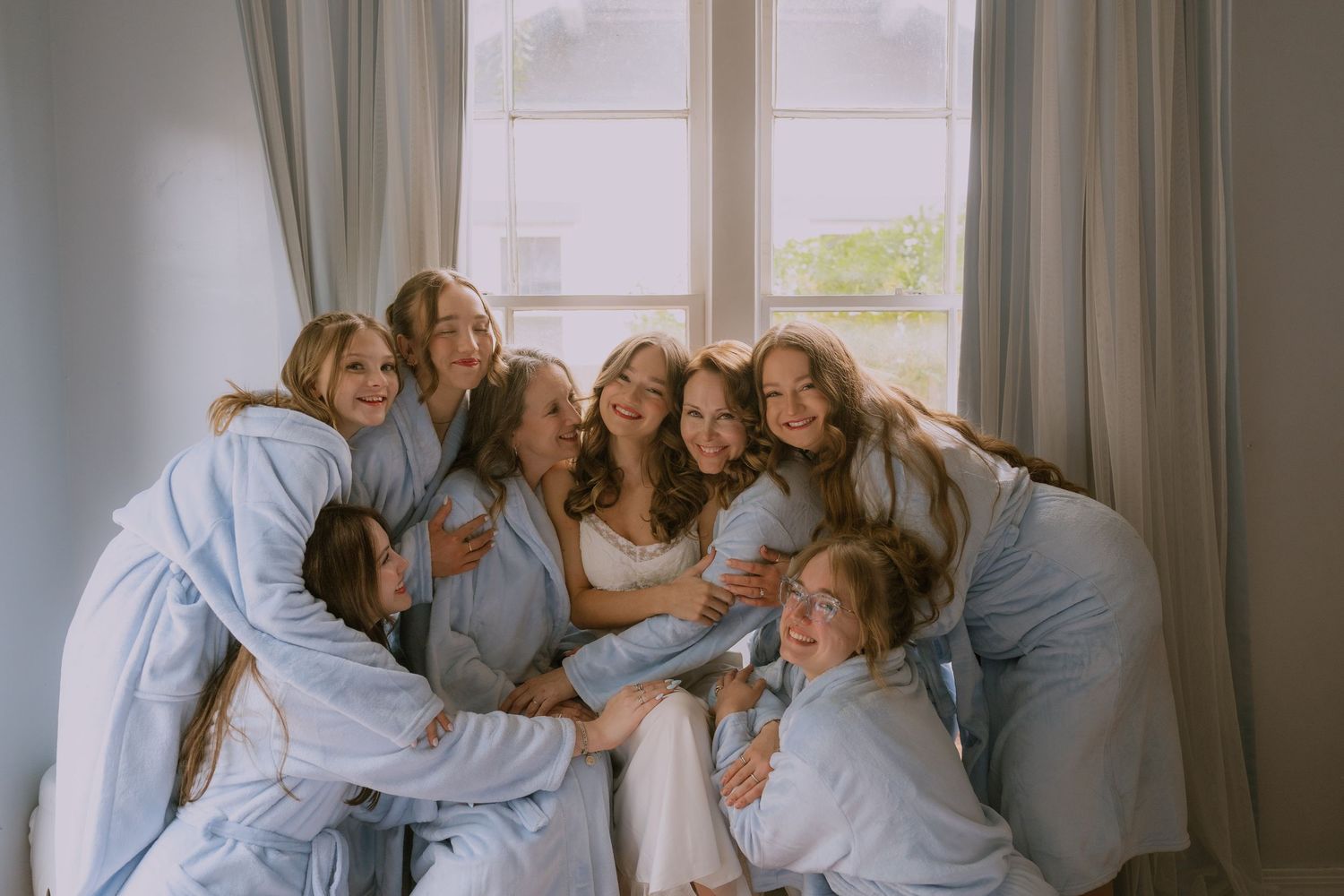 A series of candid family photos showing joyful moments and embraces in a bright, window-lit room.