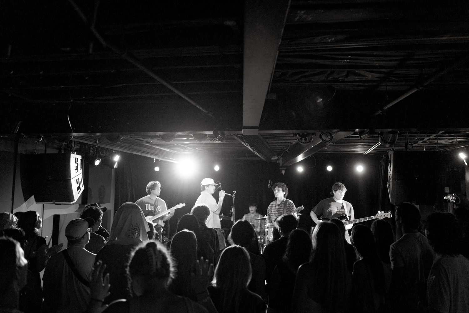 Silhouetted crowd watching a live performance on stage with dramatic concert lighting in a dark venue.