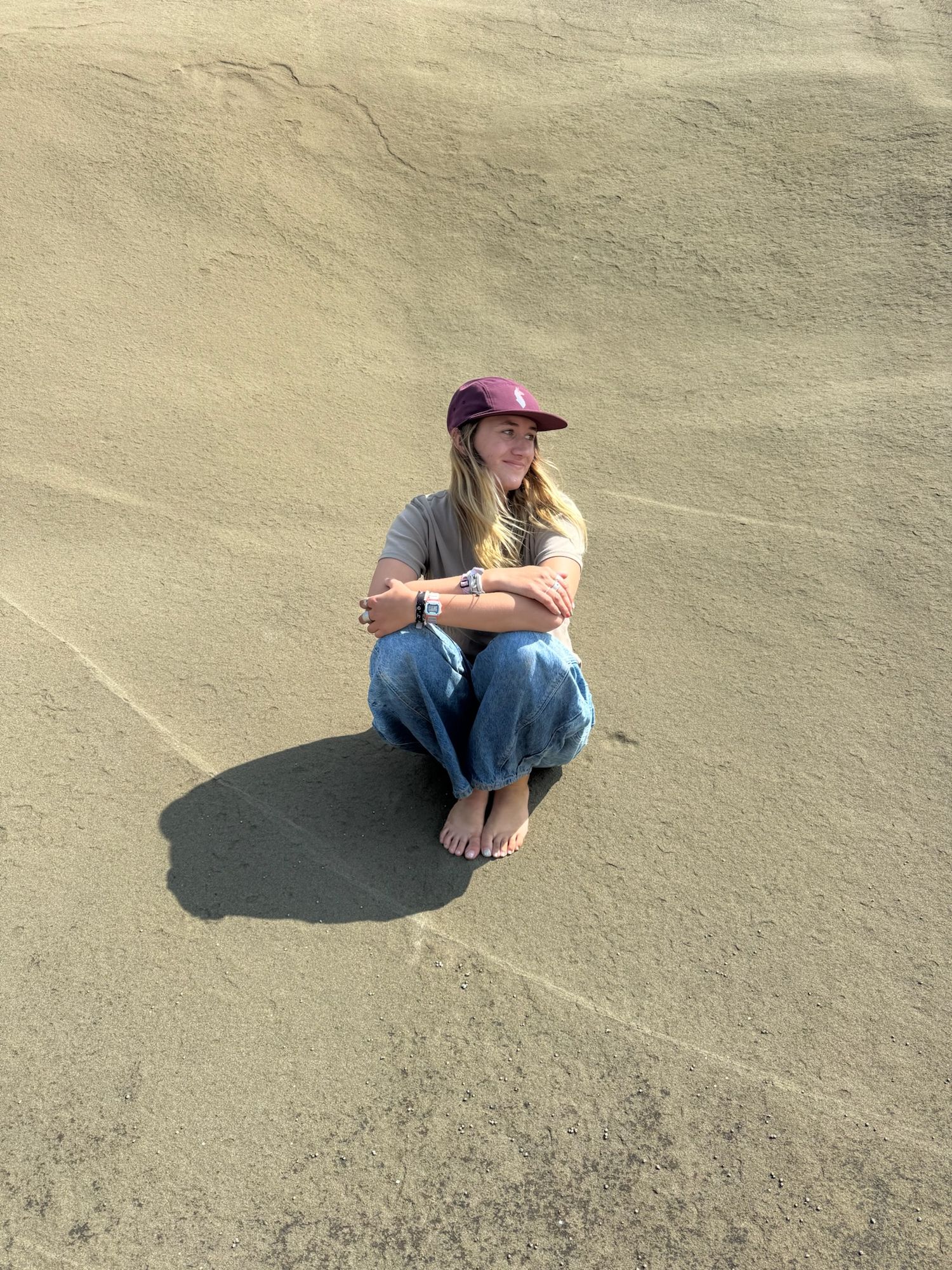 A sequence of photos showing someone sitting on sandy ground casting a shadow in different positions and angles.