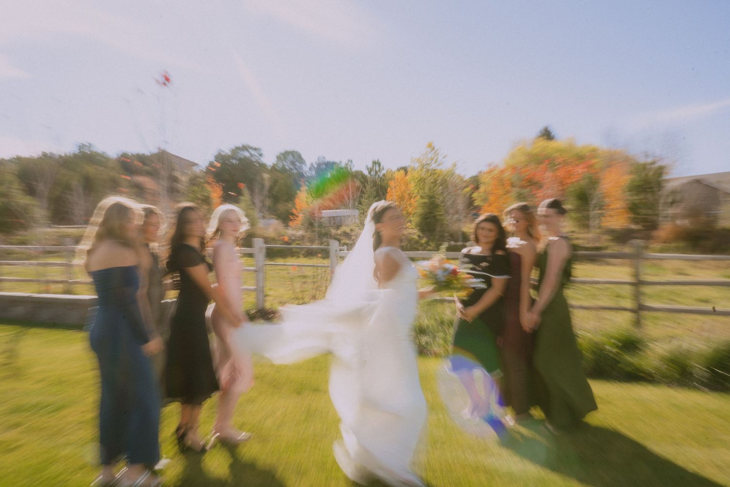 Wedding party celebrating and dancing together outdoors on a sunny autumn day.