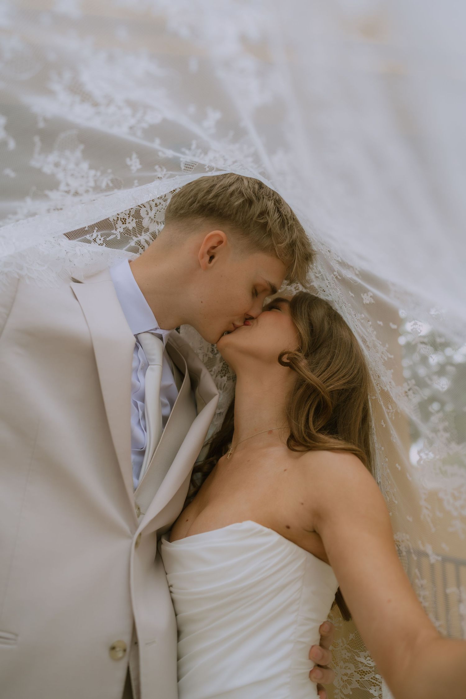 Romantic wedding couple sharing an intimate moment in soft ethereal lighting against a light background.