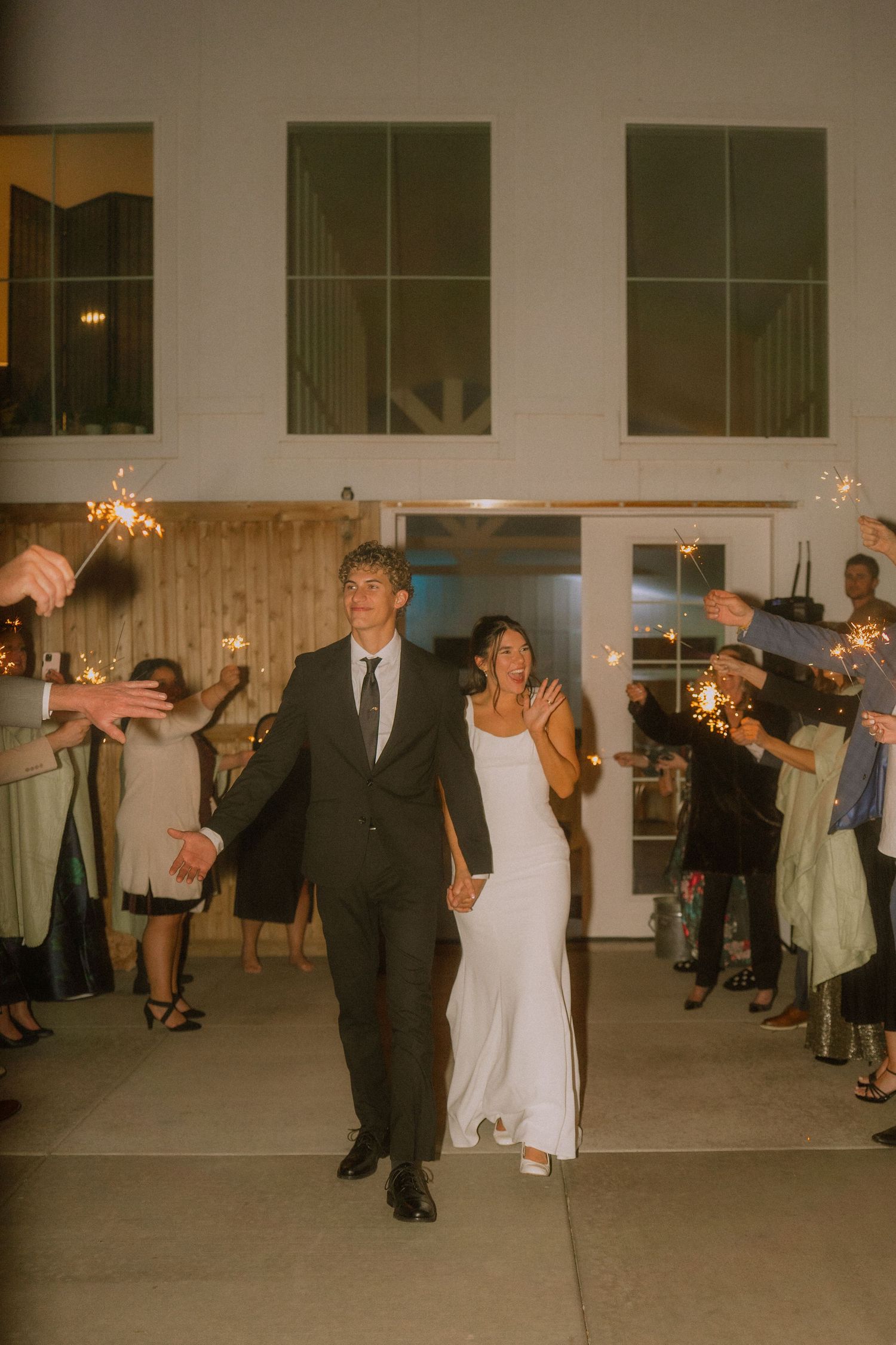 Wedding guests dance with sparklers during an indoor evening celebration.