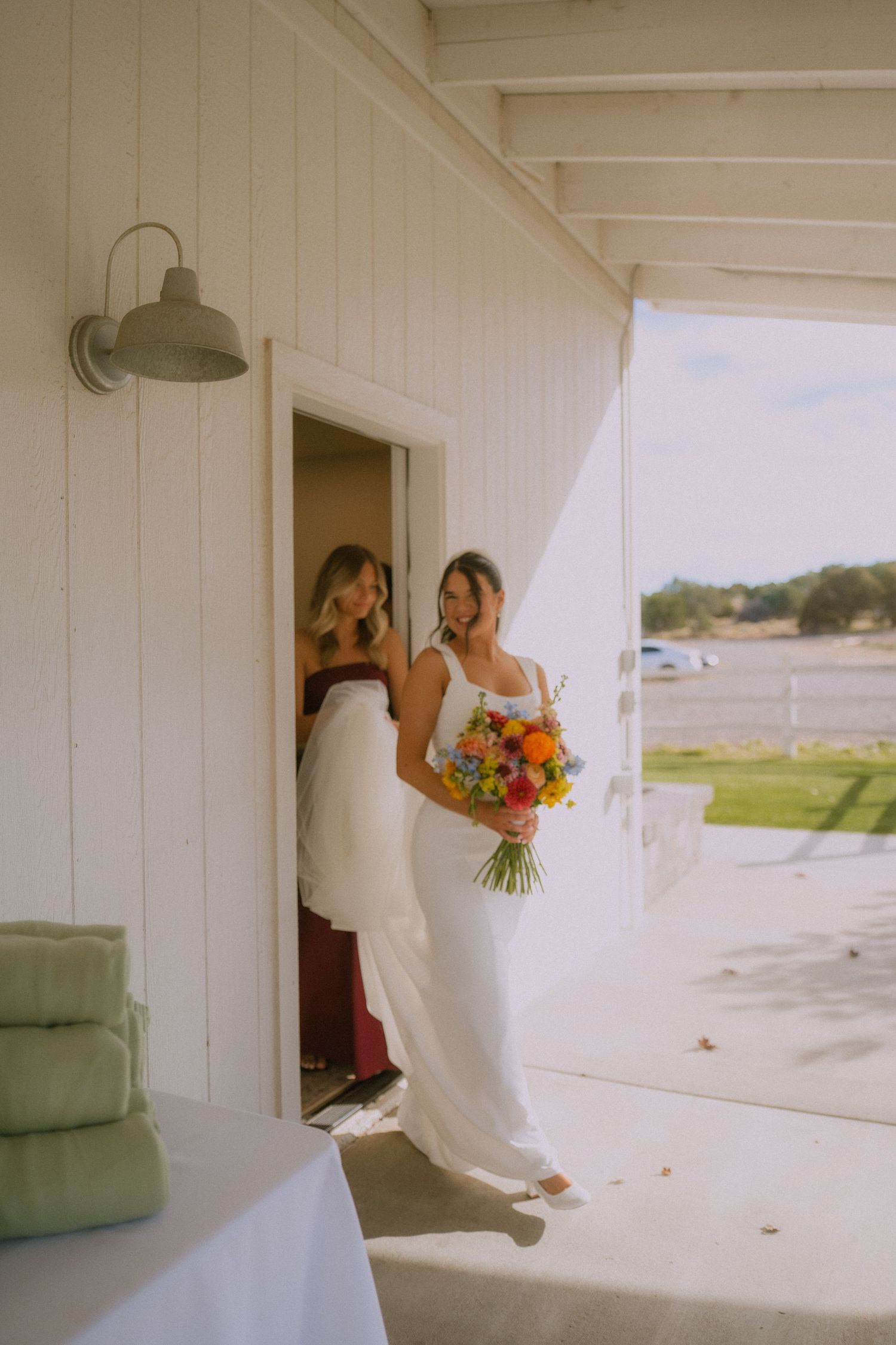 A series of candid moments showing someone in a white dress holding colorful flowers by a beach house.