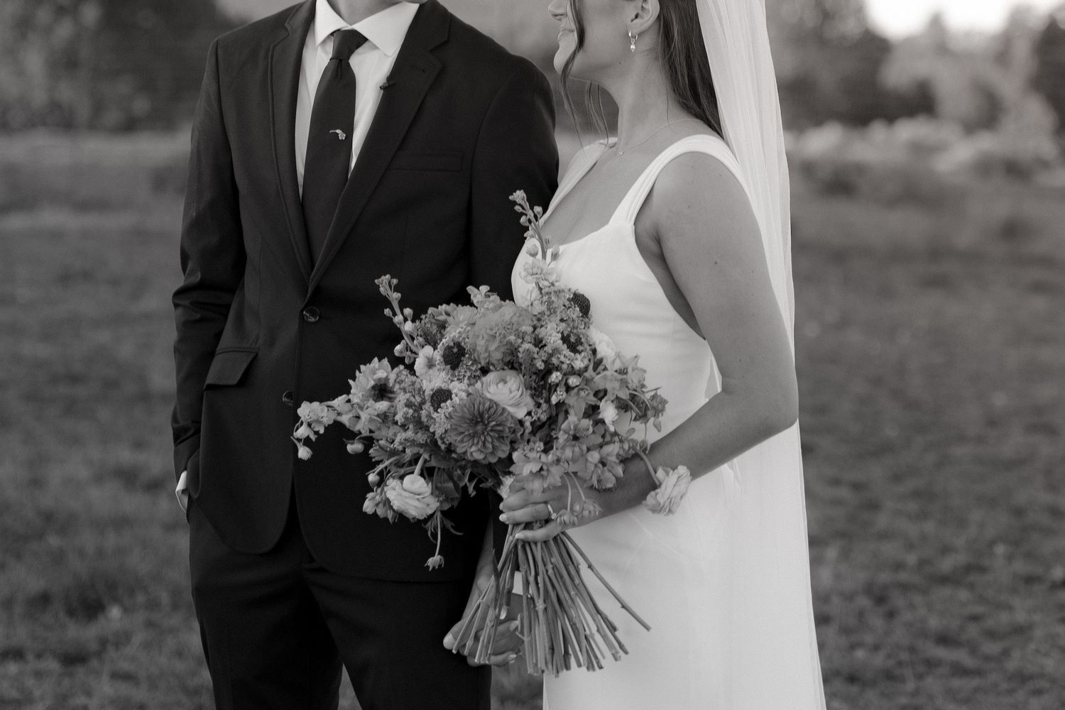 Black and white portrait of newlyweds with bride holding rustic bouquet.