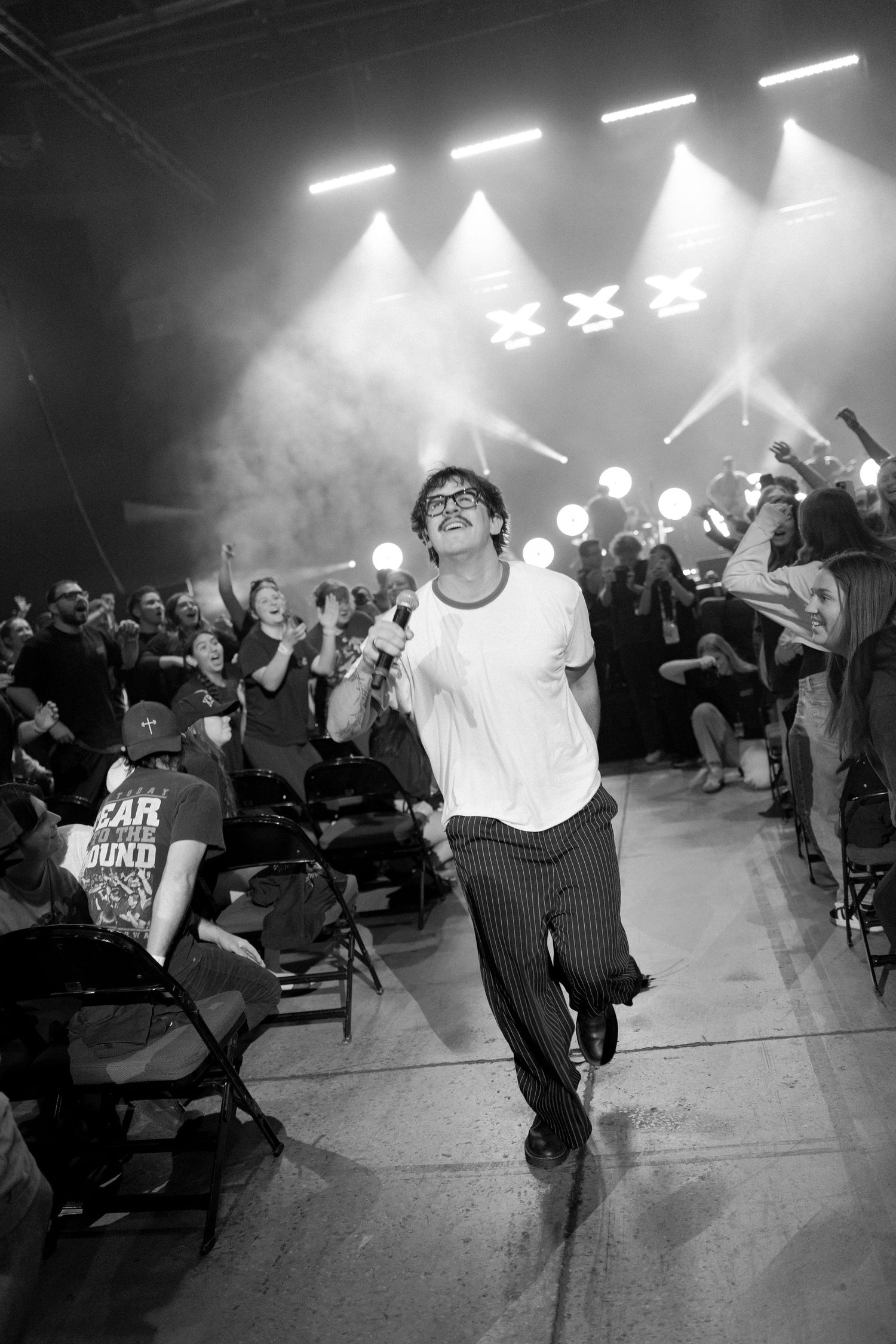 Black and white photos of energetic concert performers dancing on stage with dramatic lighting and crowd in background.