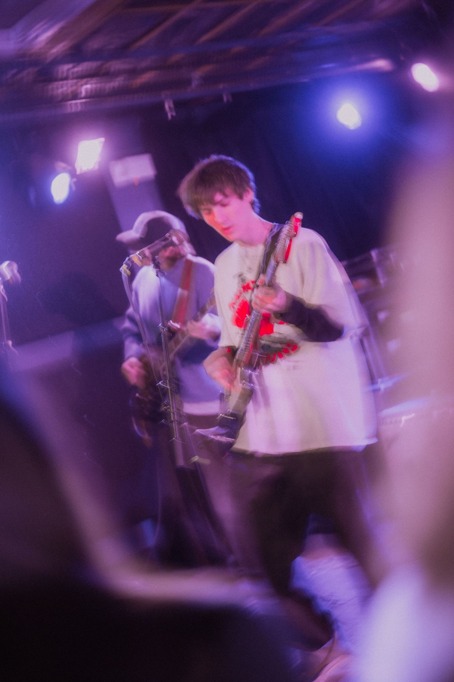 Band members play instruments in a purple-lit performance space creating an atmospheric scene.