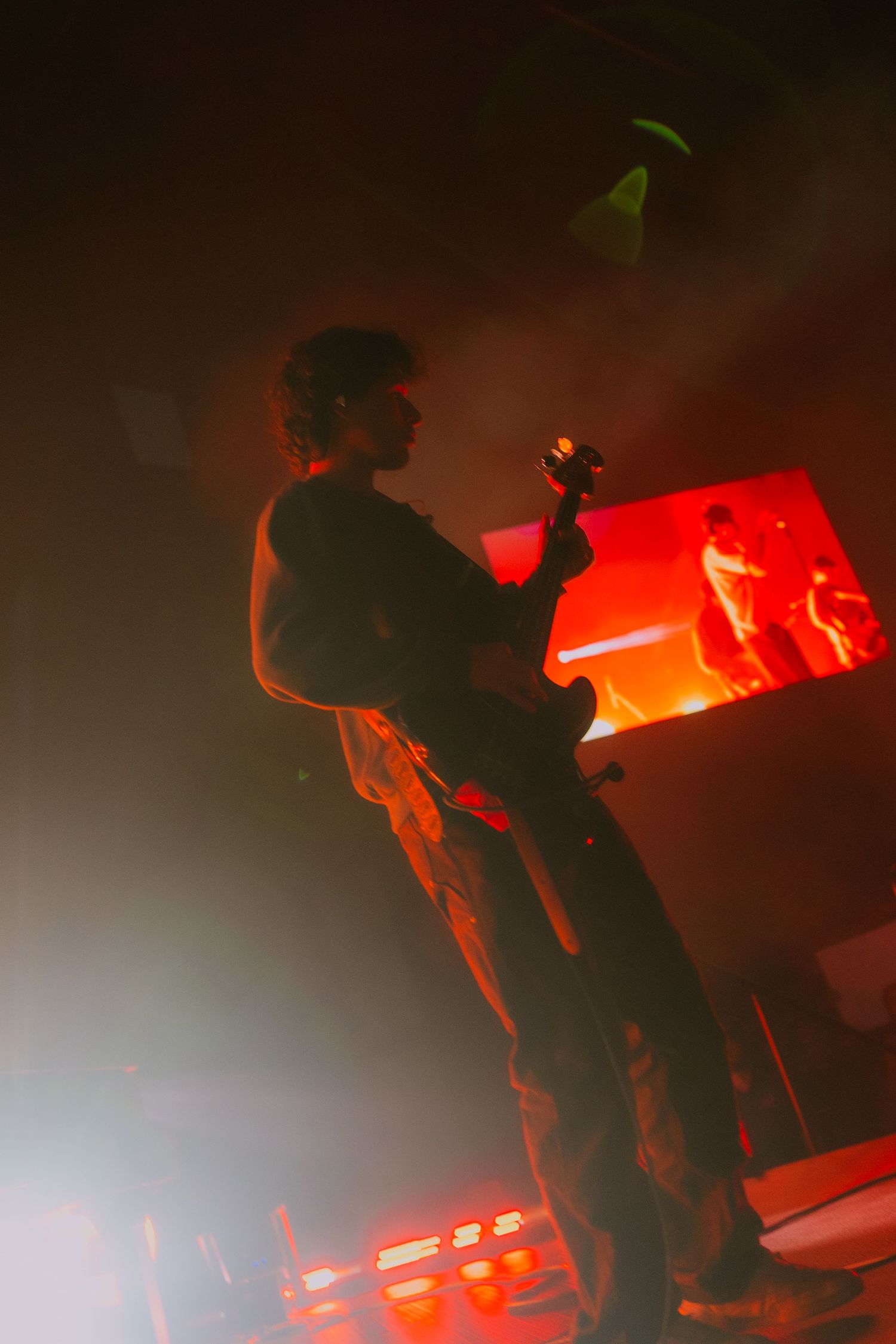 Silhouettes of performers on stage illuminated by dramatic red lighting during a concert performance.