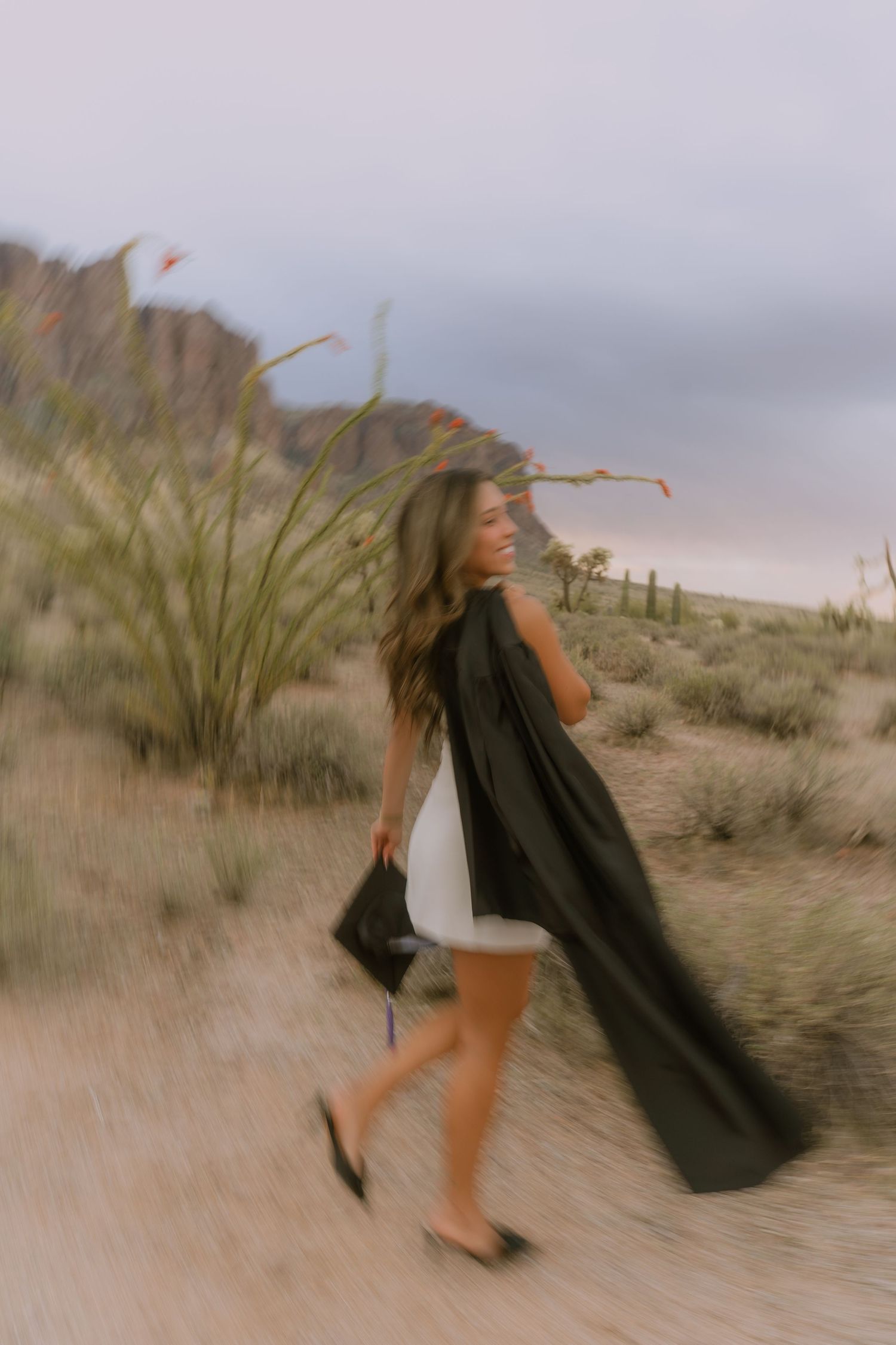 A series of motion shots capturing someone twirling in a flowing black garment against a desert backdrop.