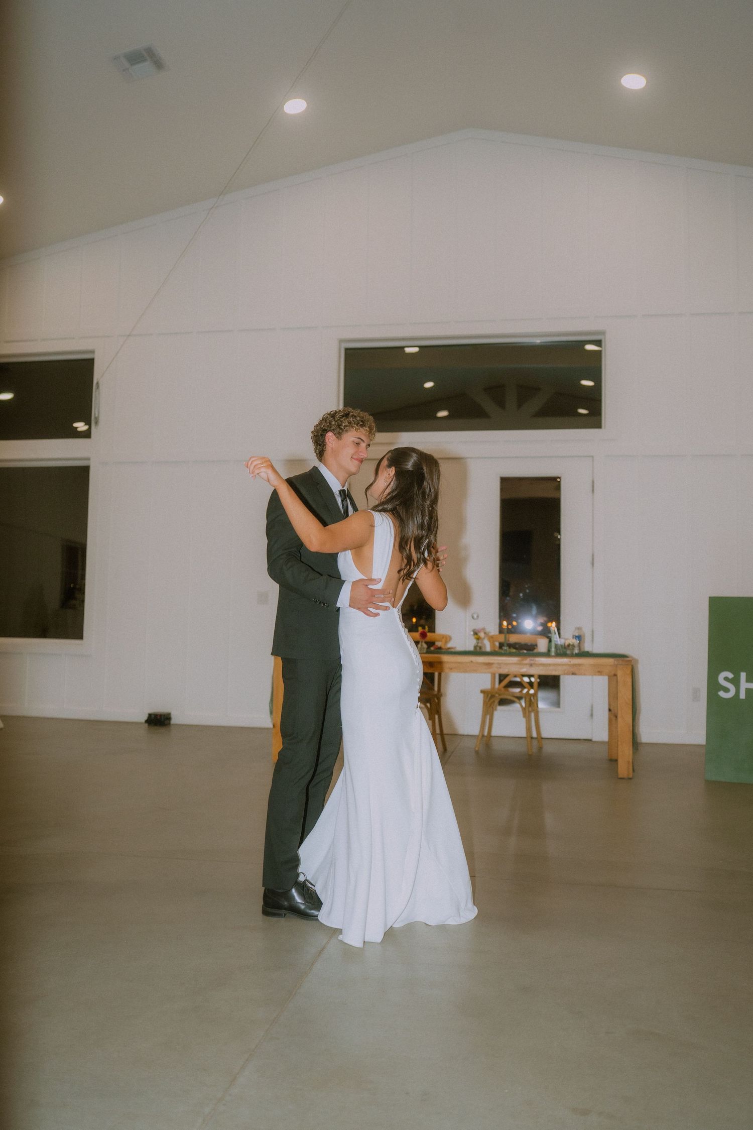 Couple shares a romantic dance moment in a minimalist white reception hall.