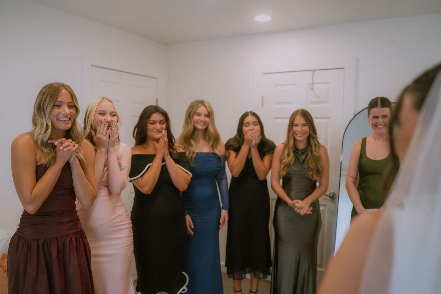 A group of friends poses together in a line against a white wall during a social gathering.