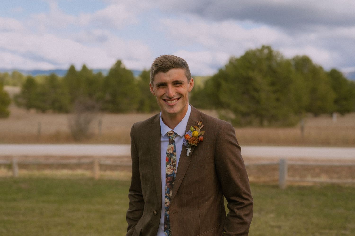 A series of candid outdoor wedding photos showing a groom in a brown suit posing in a rustic field setting.