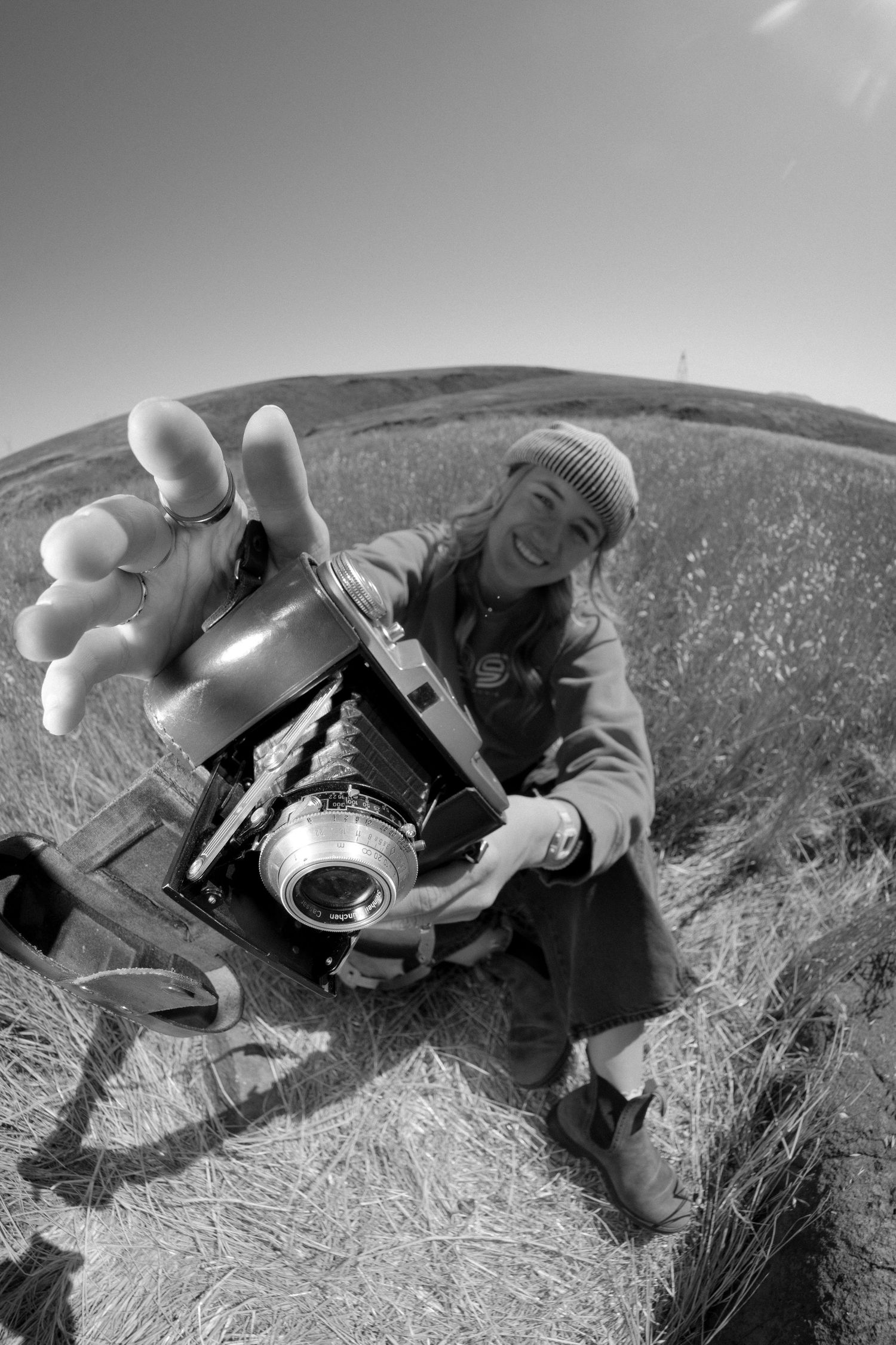 A sequence of black and white photos showing a person lying in hay while photographing with a vintage camera.
