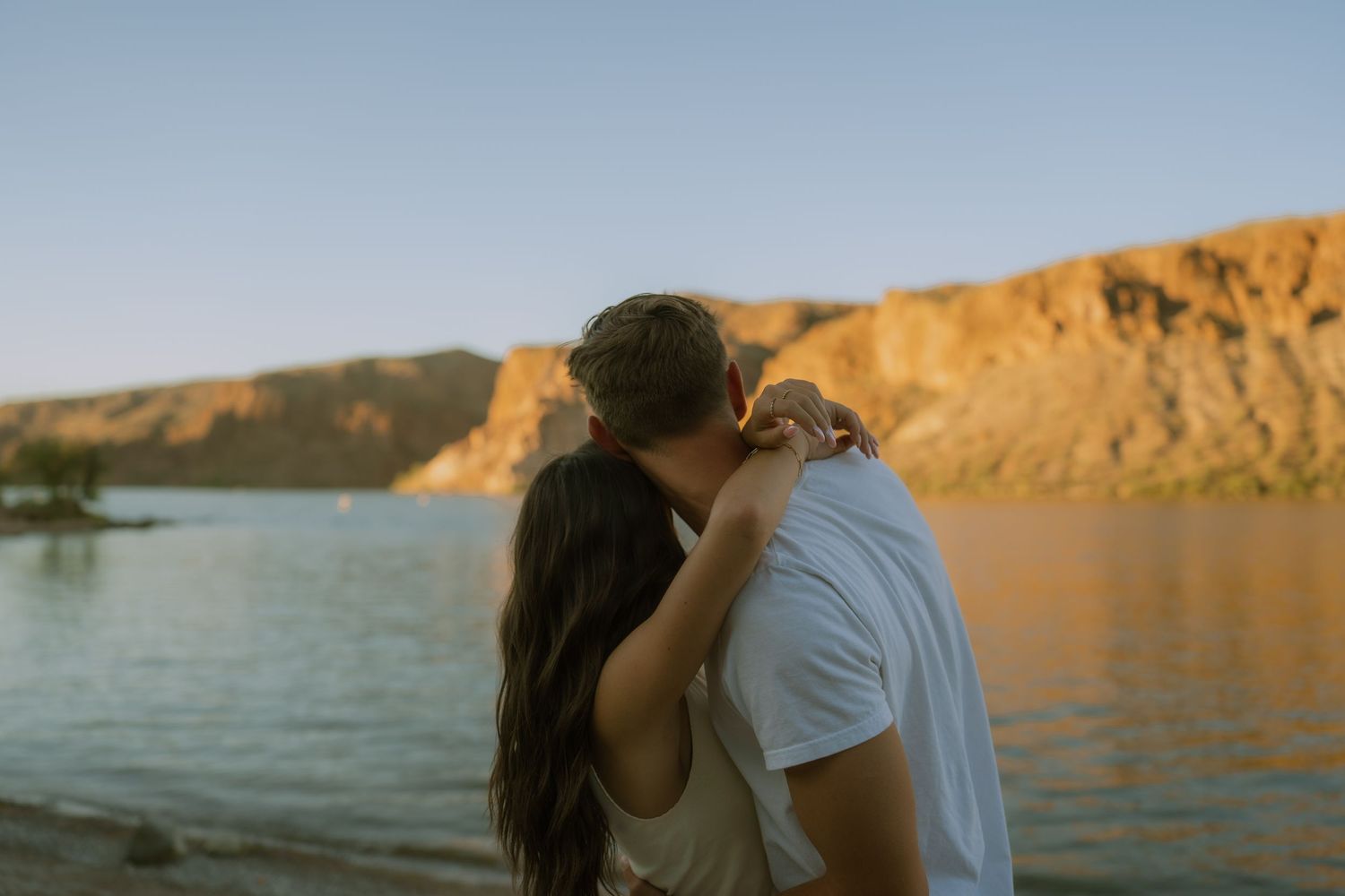 A couple shares a romantic moment at sunset by the cliffs overlooking the ocean.