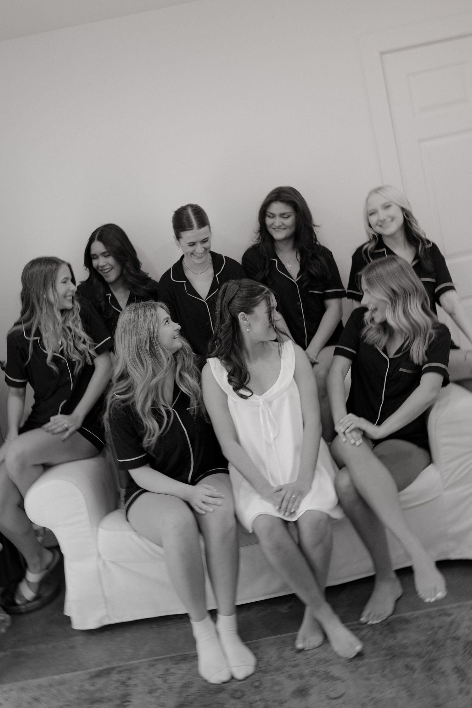 A black and white photo series showing a group sitting against a wall in casual conversation.