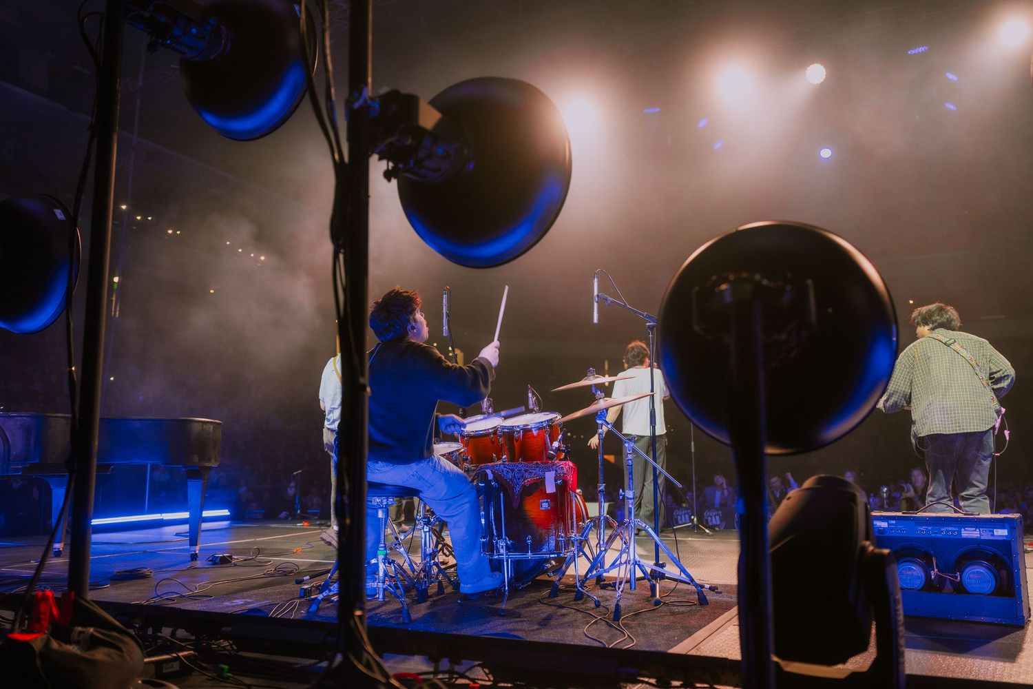 Dark concert stage illuminated with blue lighting and musical equipment setup for a performance.