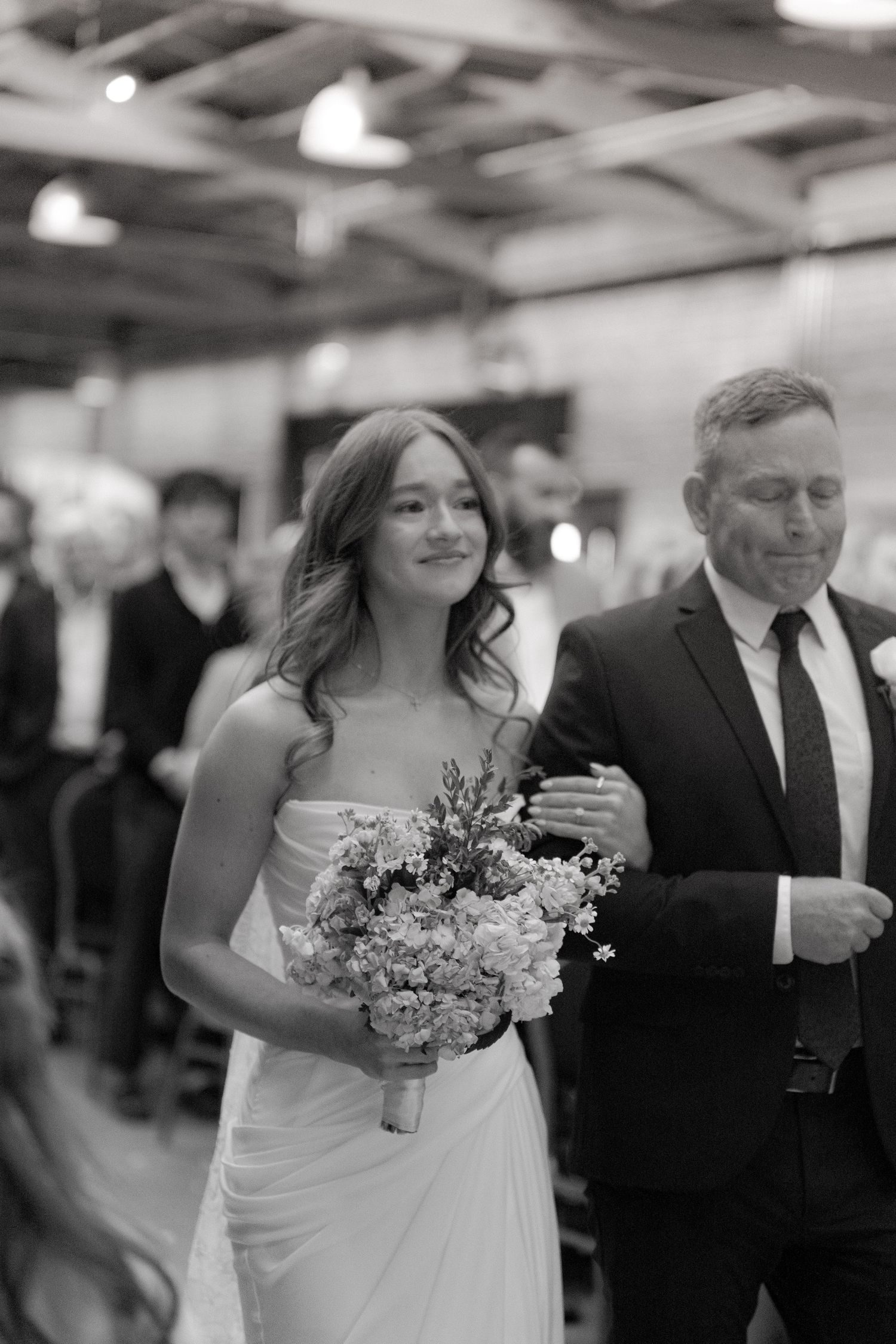 Black and white wedding ceremony processional photos showing emotional moments in an indoor venue.