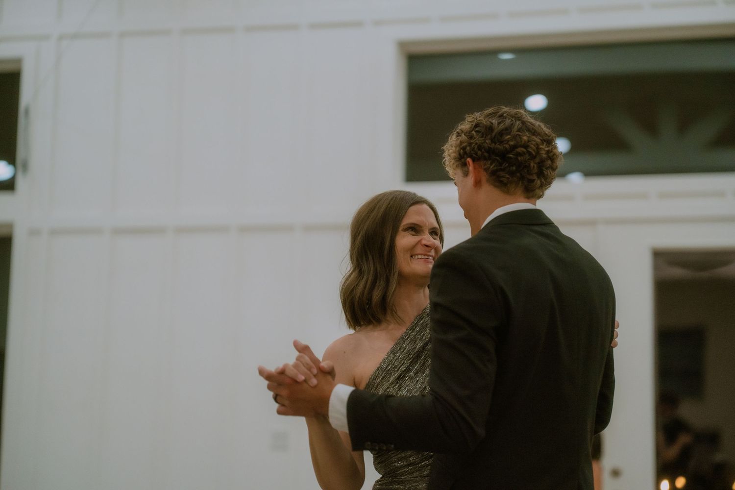 Guests mingle during an indoor wedding reception with white decor.