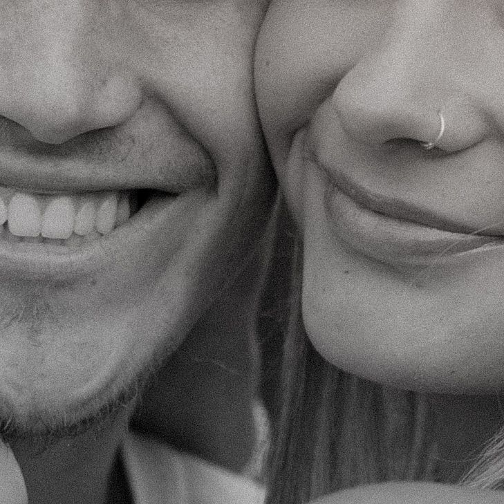 Black and white close-up photo showing a series of smiling mouths arranged in a horizontal row.