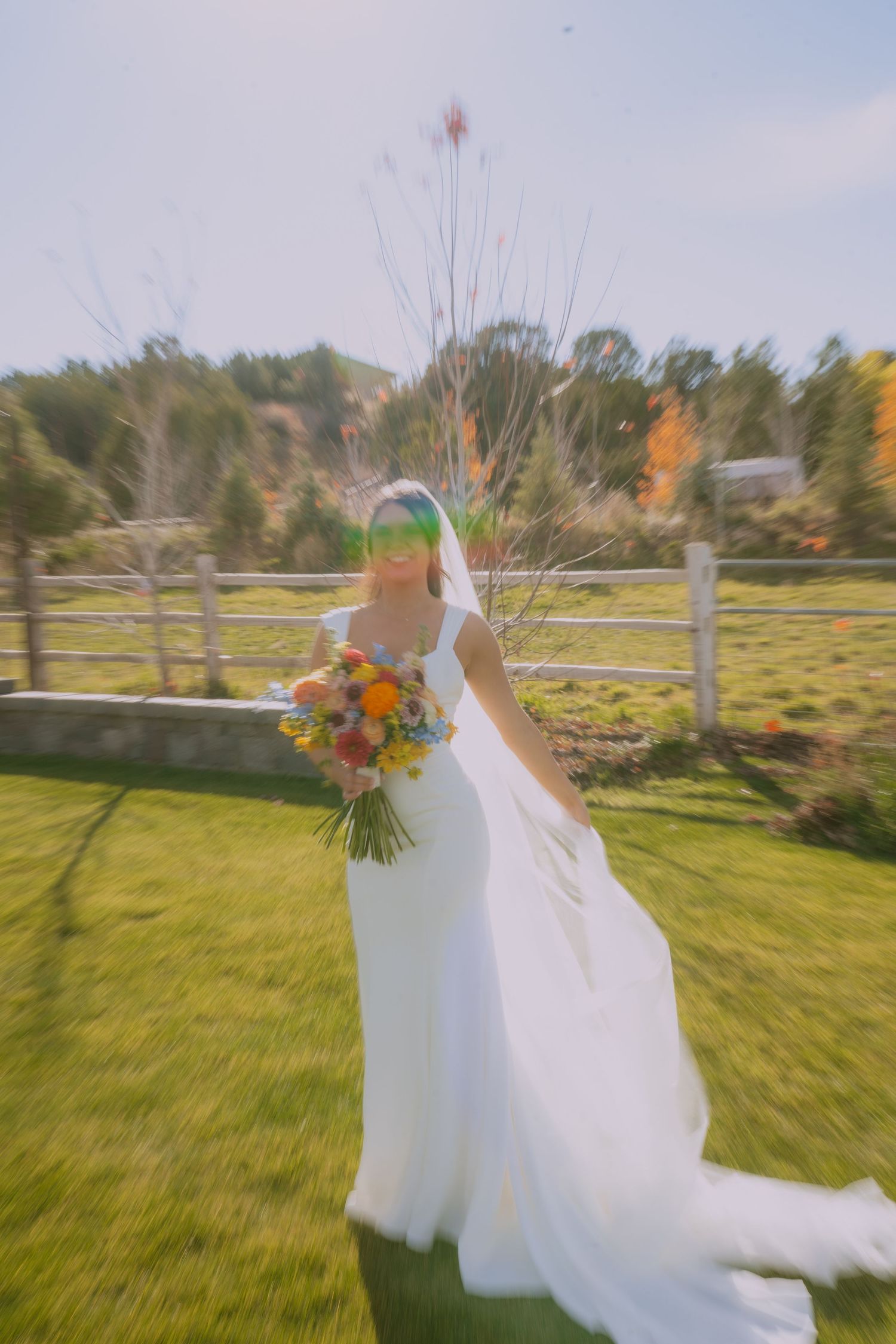 A flowing white wedding dress twirls in motion against a scenic autumn landscape with green grass and trees.