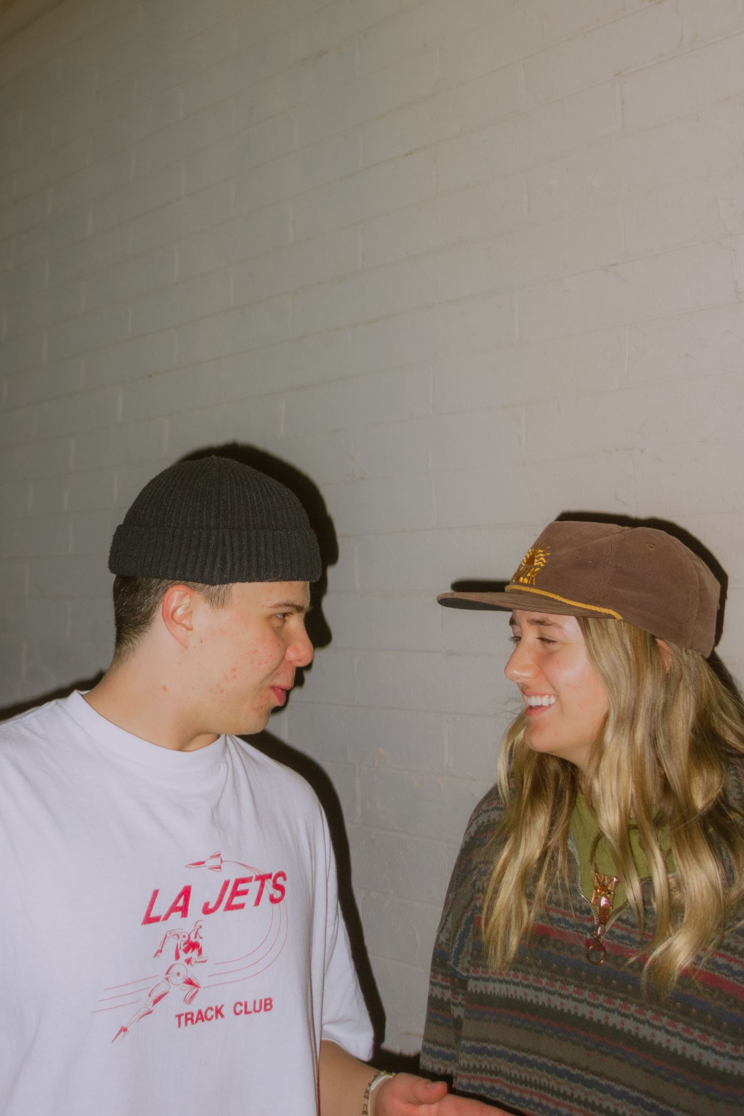 A sequence of candid moments showing two people in casual attire sharing laughter and conversation against a white wall.