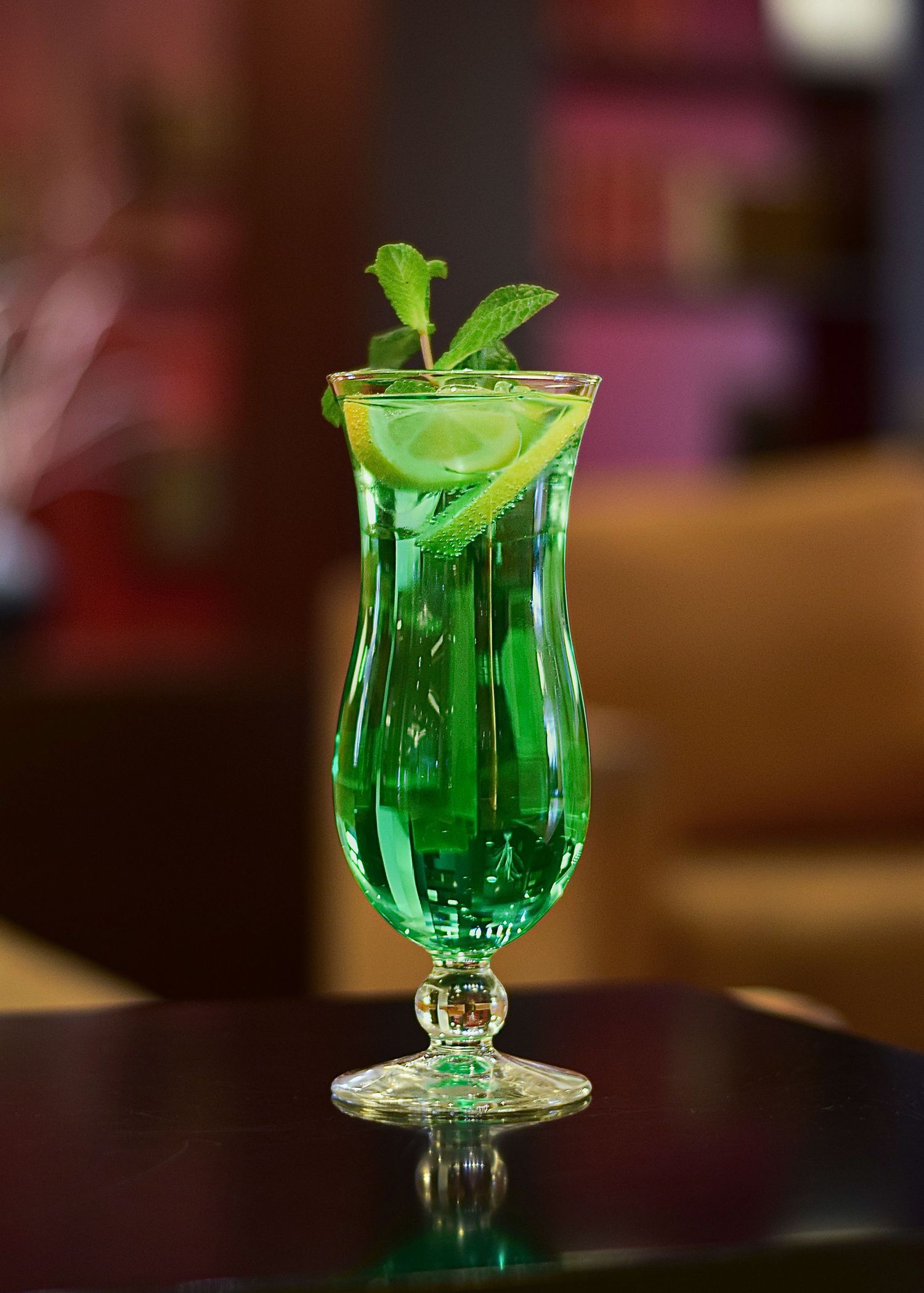 Zelený drink ve vysoké sklenici. Makro záběr koktejlu na stole. Food styling.
