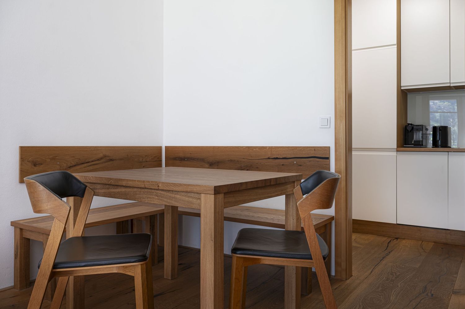 Moderní kuchyně s jídelním koutem. Designové židle Ton u stolu. Prostor pro stravování a sociální interakci v interiéru apartmánu.