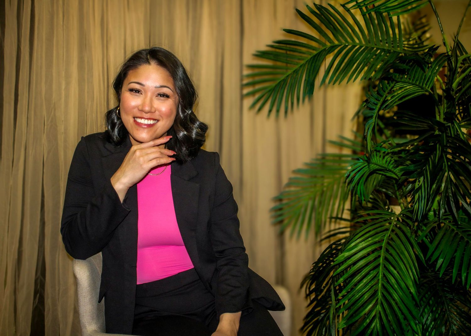 Professional portrait session with black blazer and pink top against tropical backdrop.