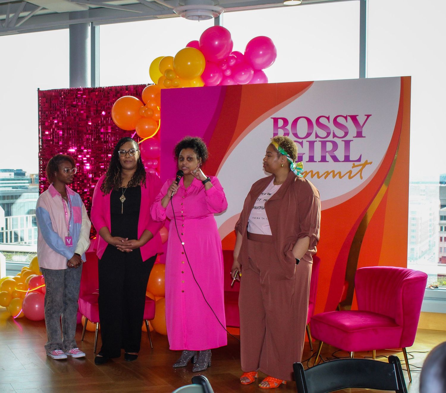 Event setup with pink and orange balloon arch and 'Bossy Girl' signage.