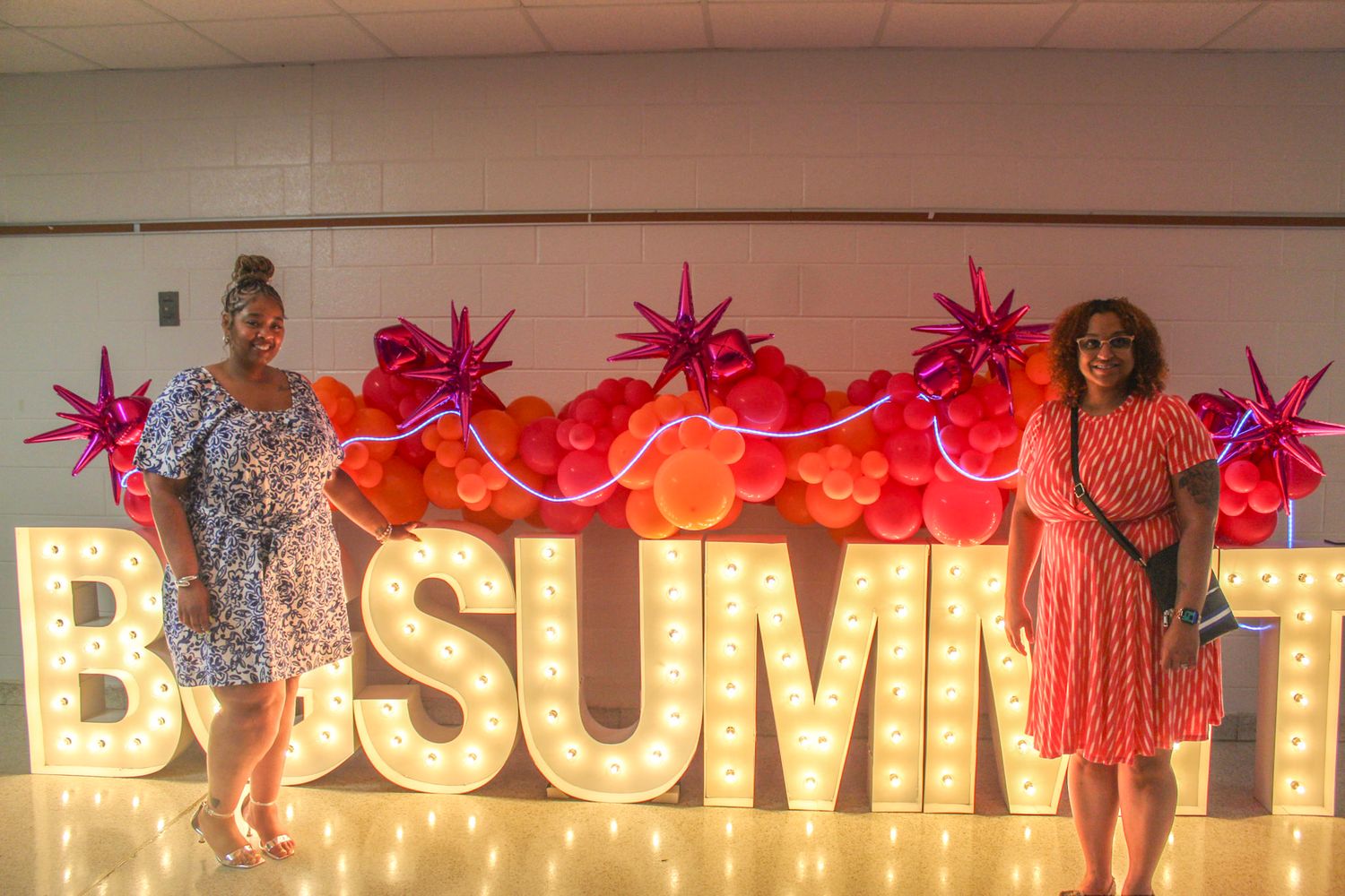An illuminated 'BG SUMMIT' sign display with pink decorative elements.